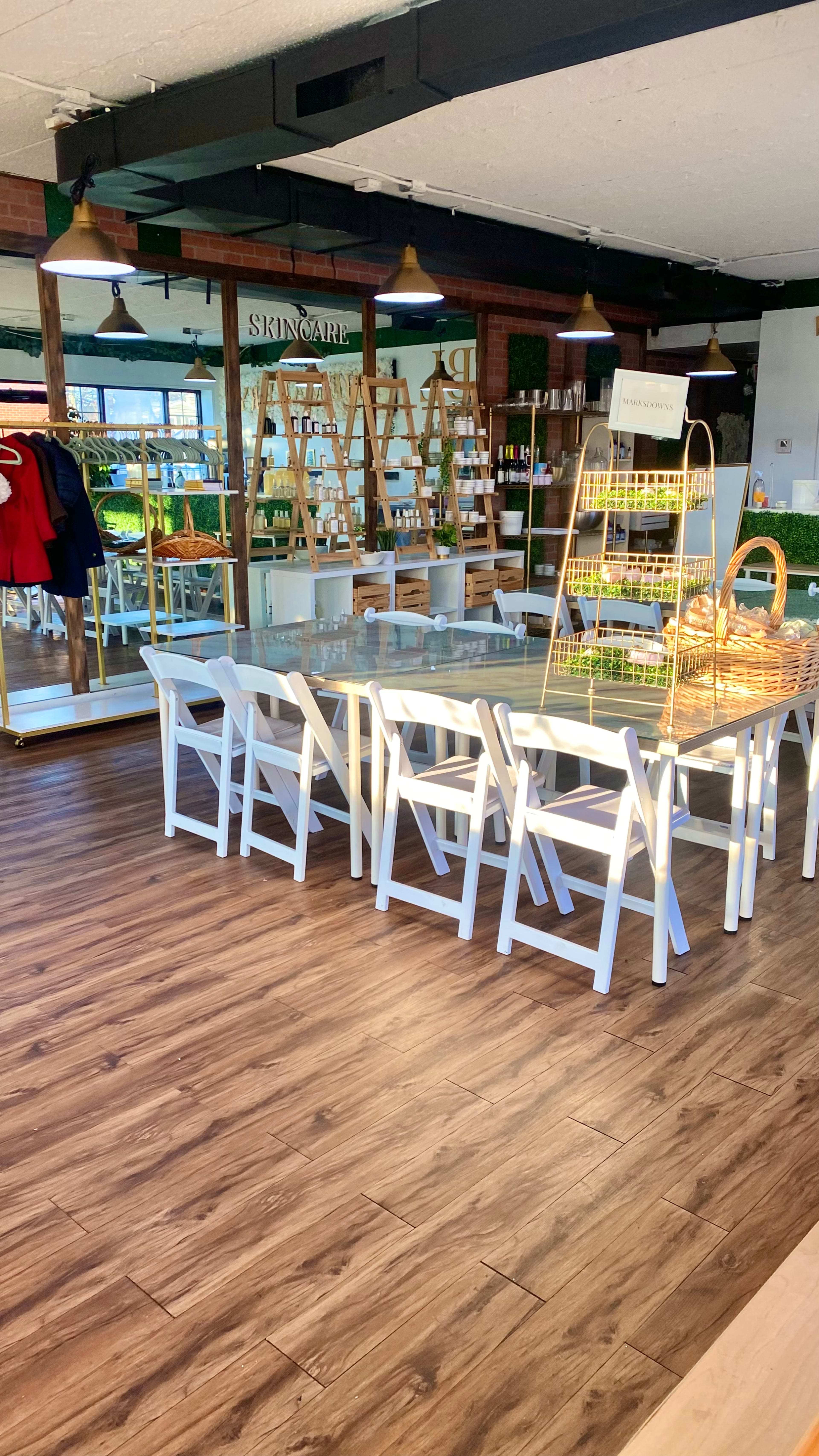 A clean and modern skincare shop with wooden flooring, white furniture, and shelves displaying products.