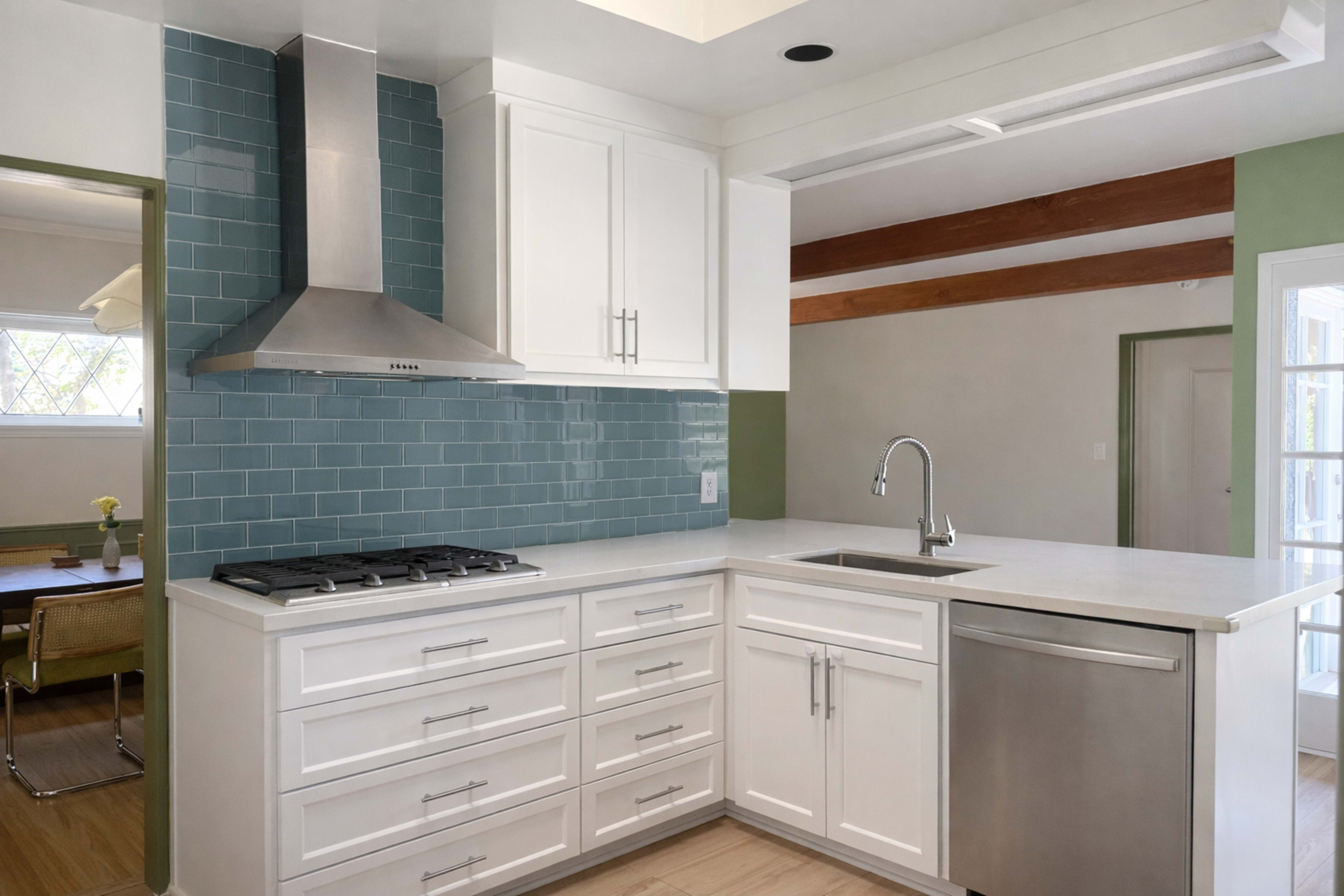 The image showcases a modern kitchen featuring white cabinetry, a stainless steel sink, and a turquoise tiled backsplash.