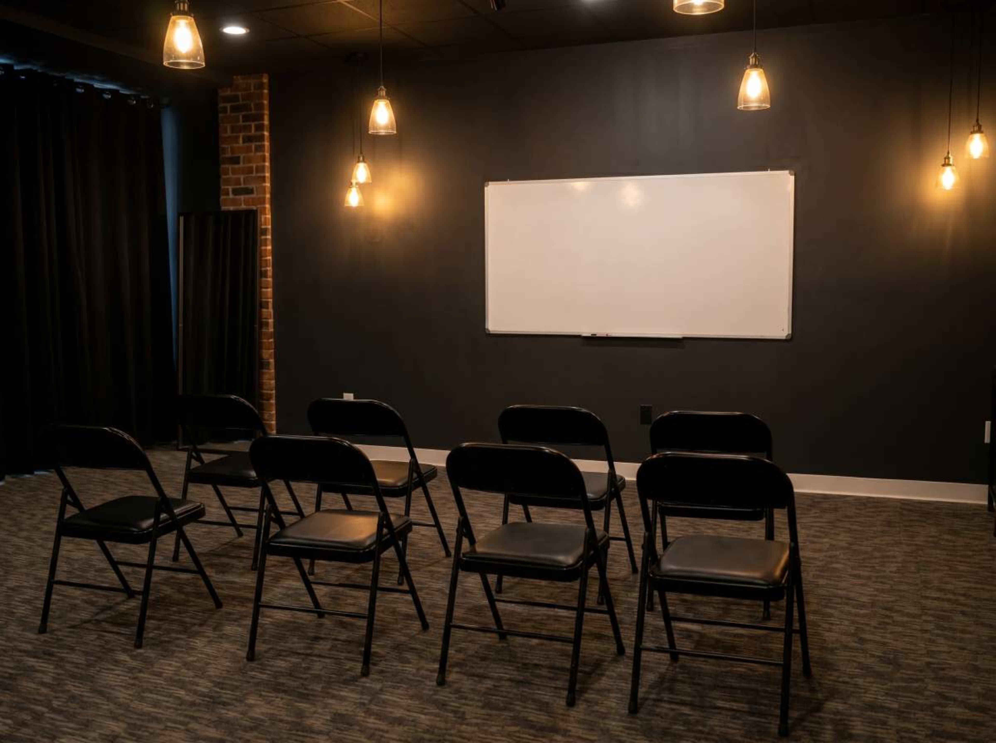 A small room with black folding chairs arranged in a semi-circle facing a whiteboard.