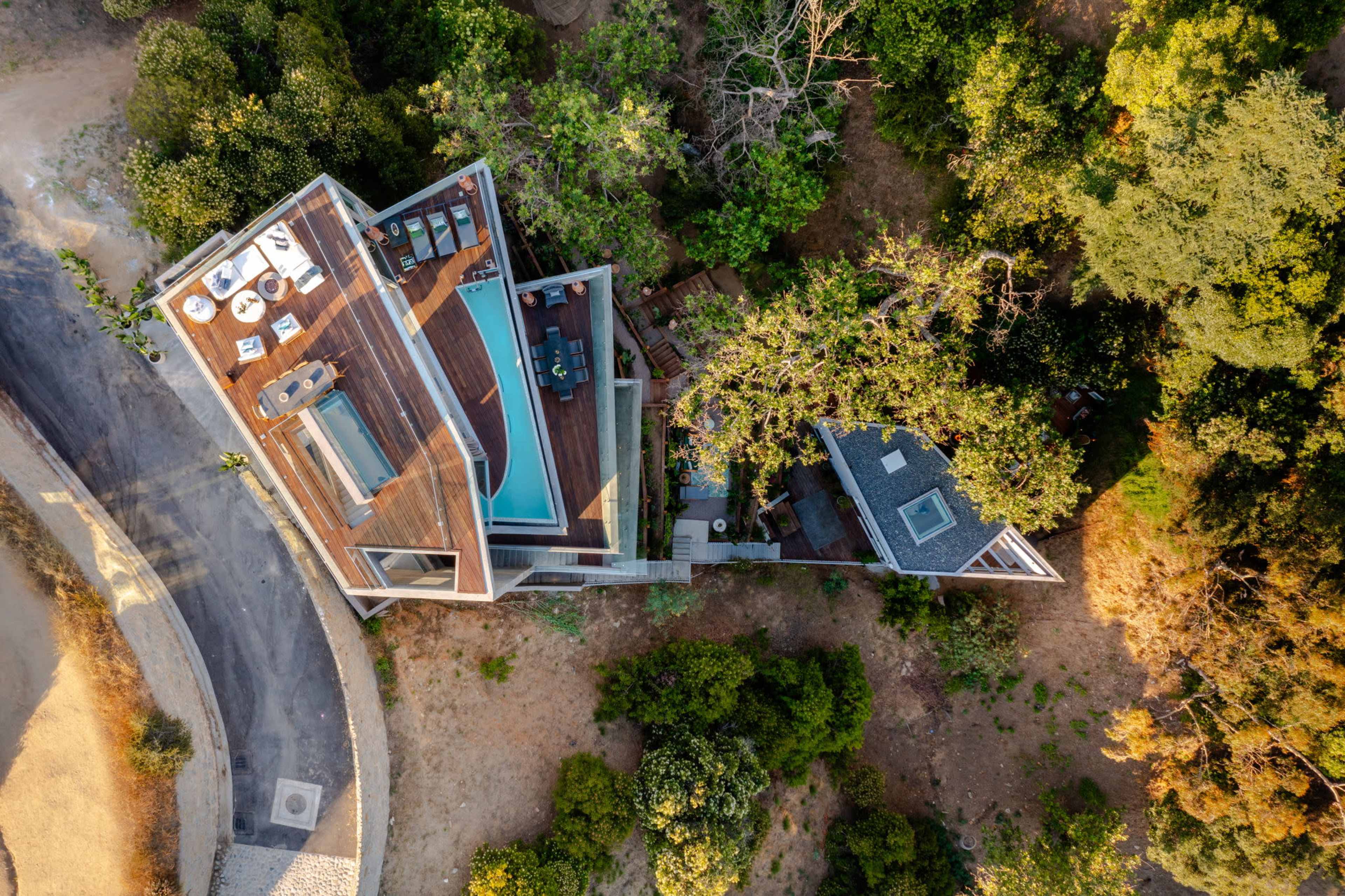 An aerial view shows a modern house with a pool and surrounding greenery.