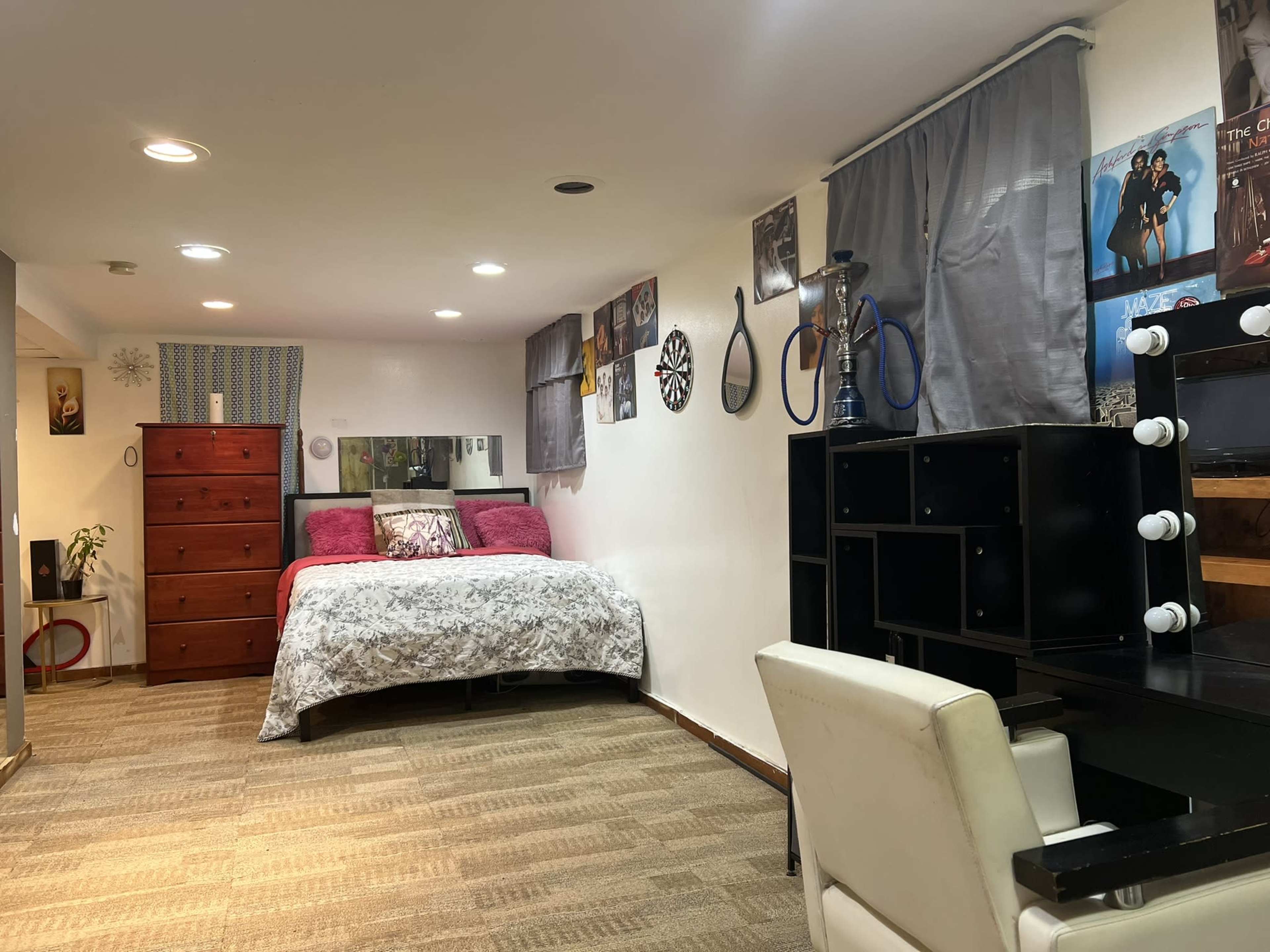 A neatly arranged bedroom with a bed, dresser, and desk, featuring decorative posters on the walls.