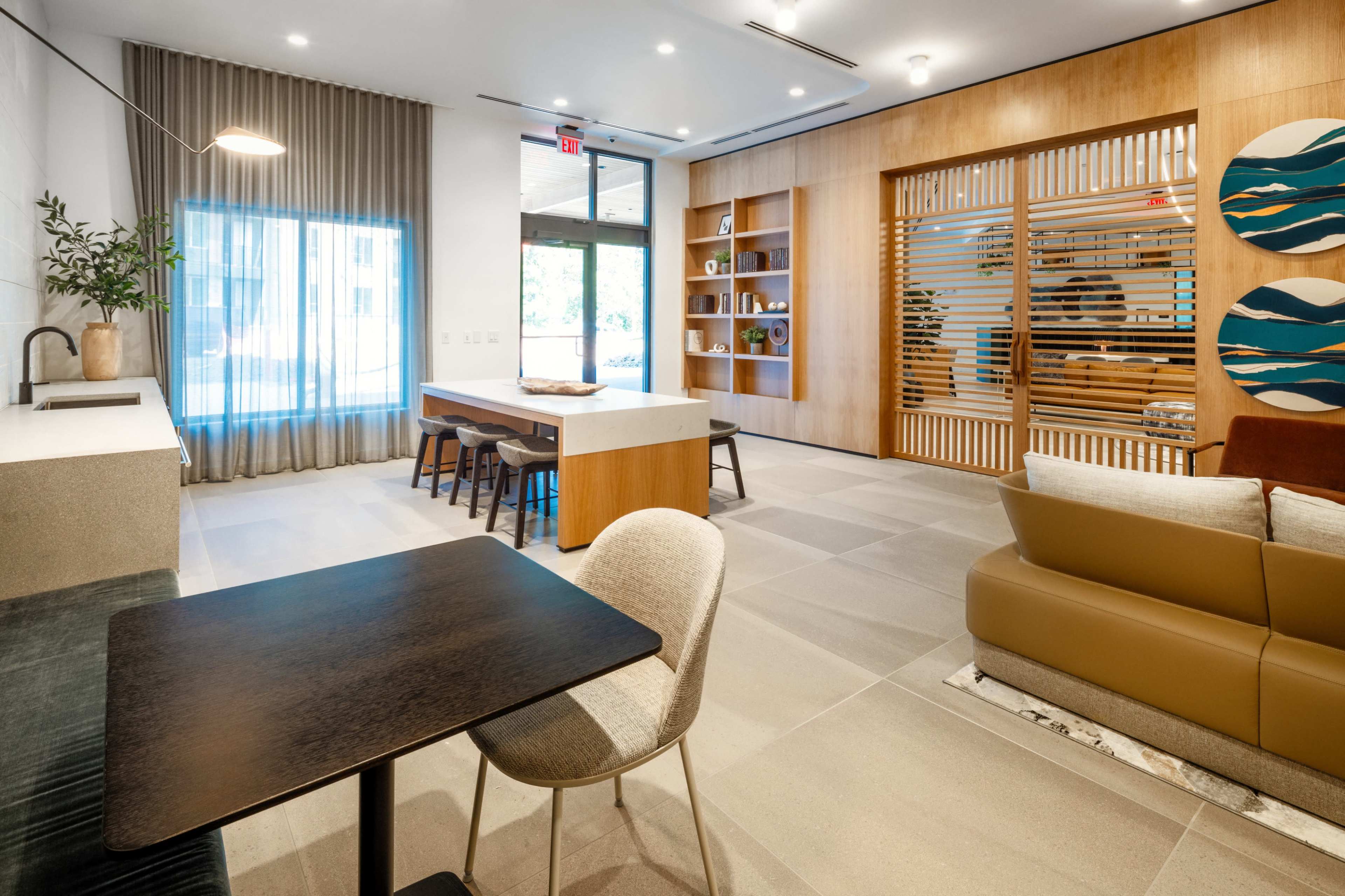 The image features a modern, open living space with a kitchen table, chairs, and a lounge area adorned with wooden accents and decorative wall art.