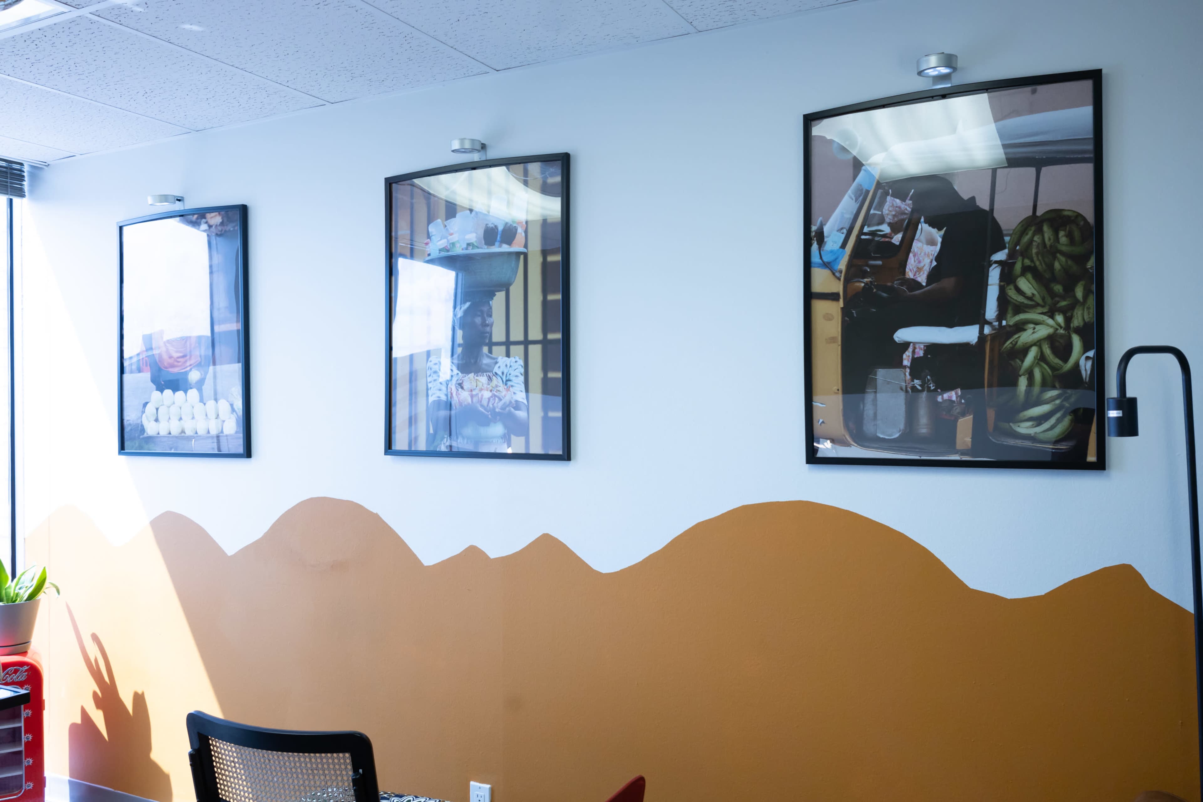 A wall with three framed photographs and a section of painted brown resembling a mountain range.
