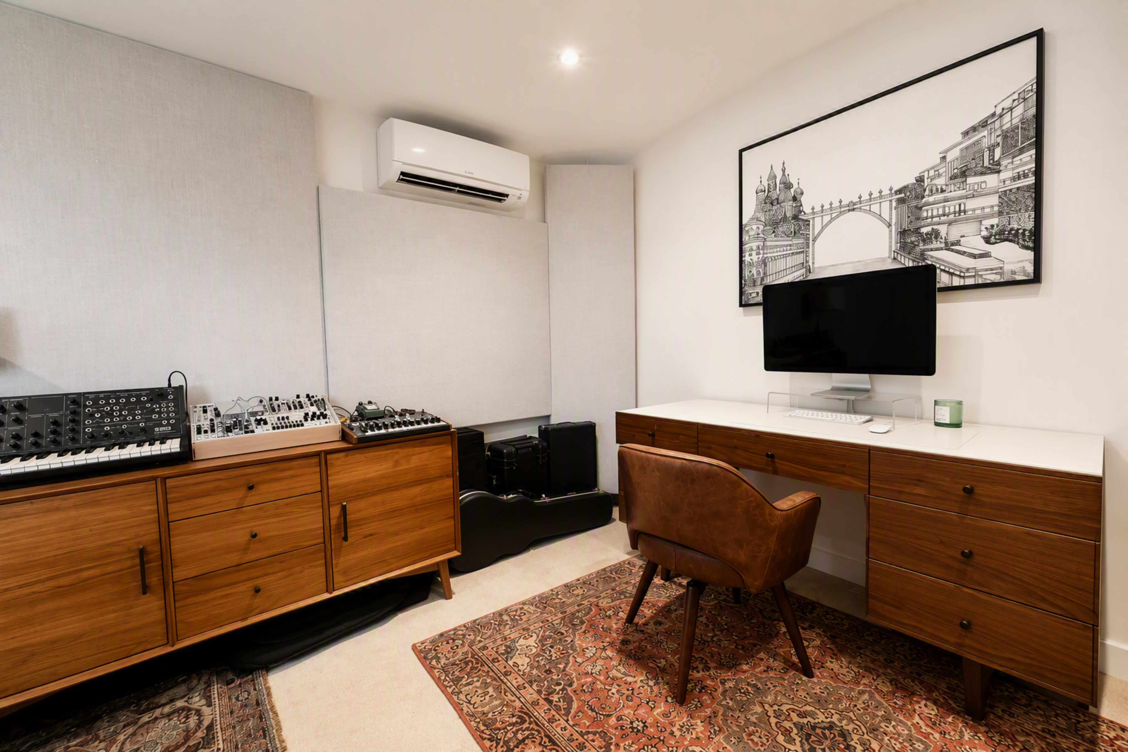 The image depicts a sleek home office featuring a desk with a computer, a vintage-style chair, and an audio equipment setup along one wall, accented by a large black-and-white artwork.