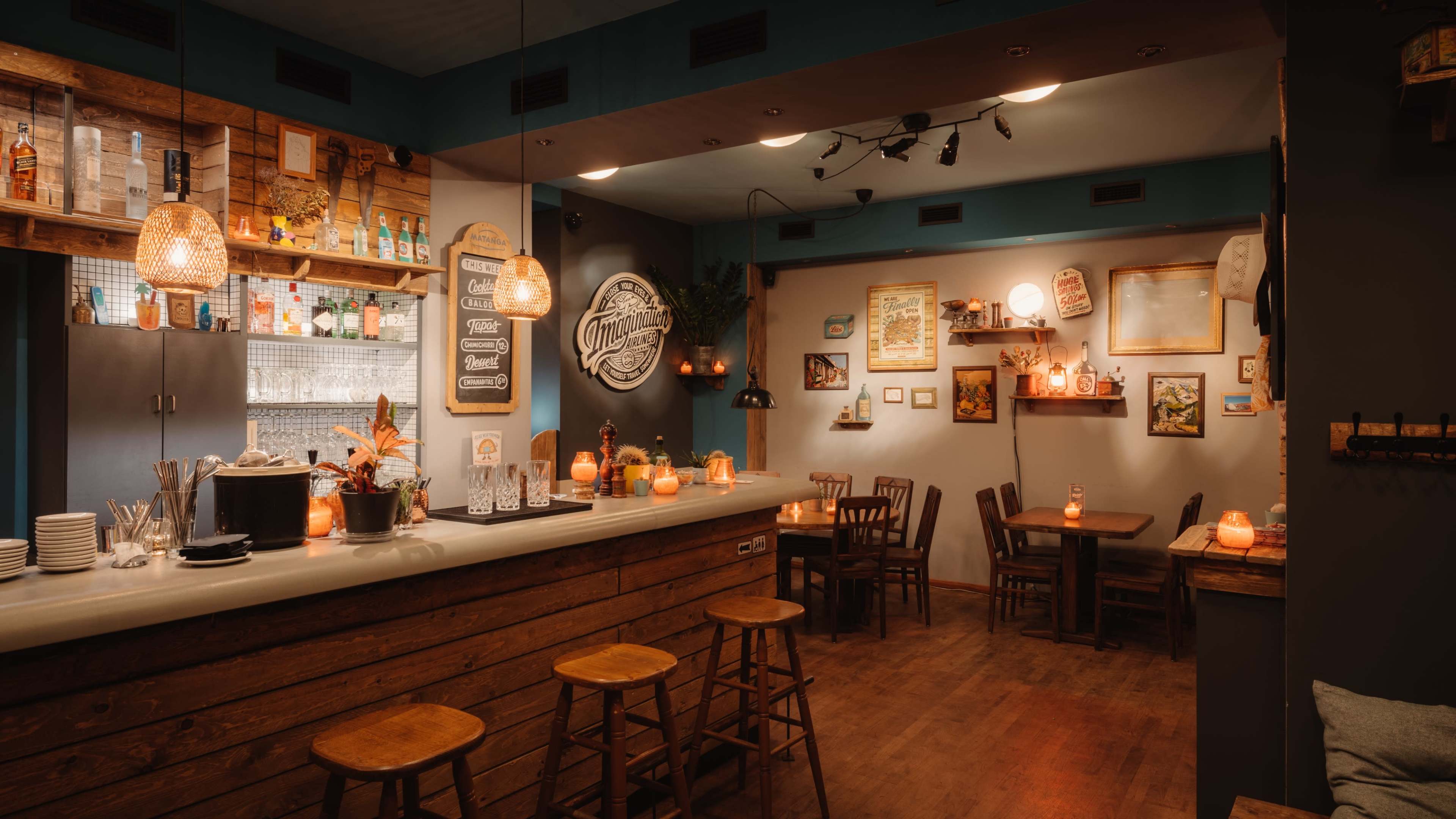 A cozy bar interior featuring wooden furniture, decorative wall art, and warm lighting.