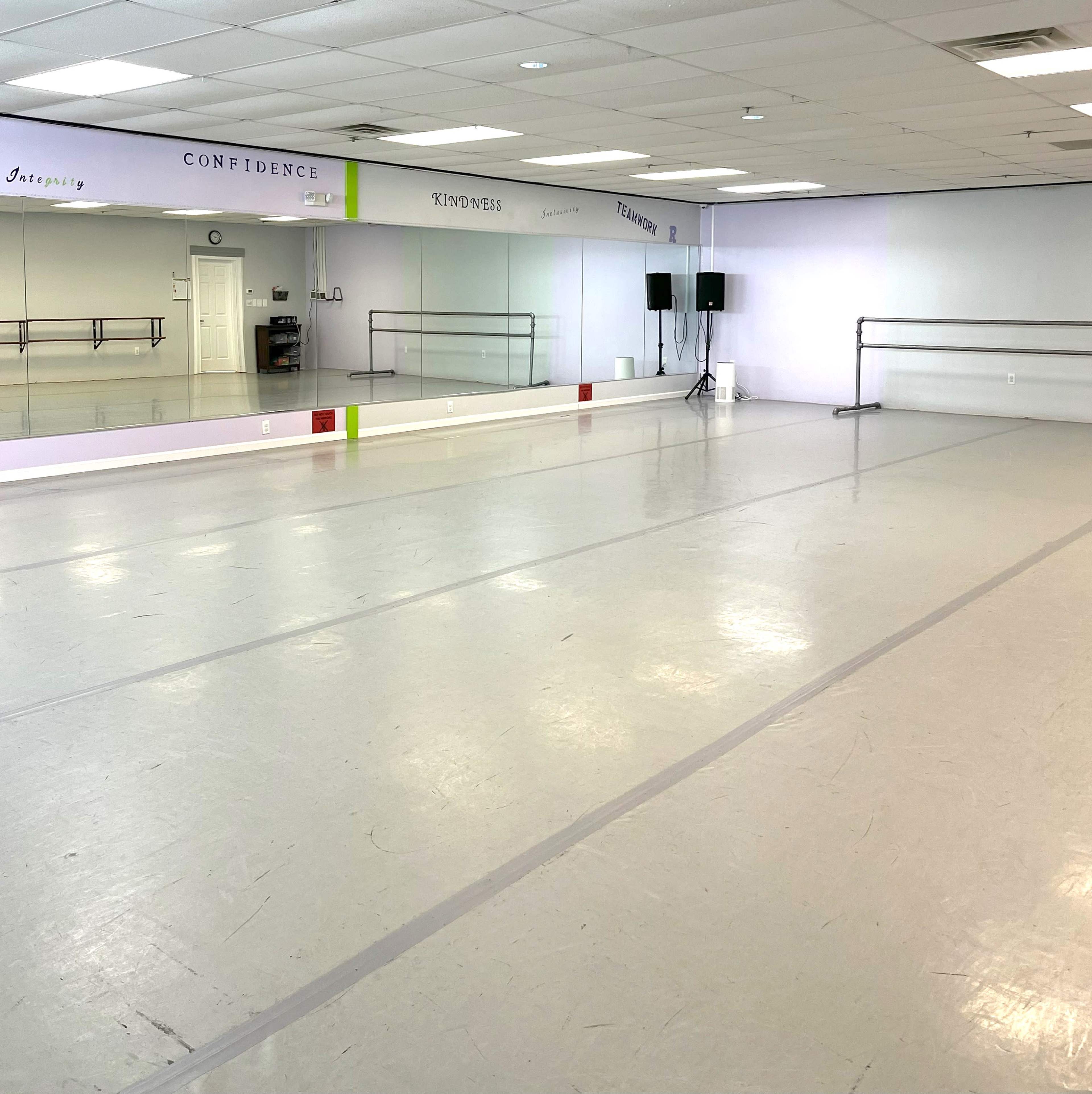 The image shows a mirrored dance studio with wooden ballet bars, speakers, and motivational words written on the walls.