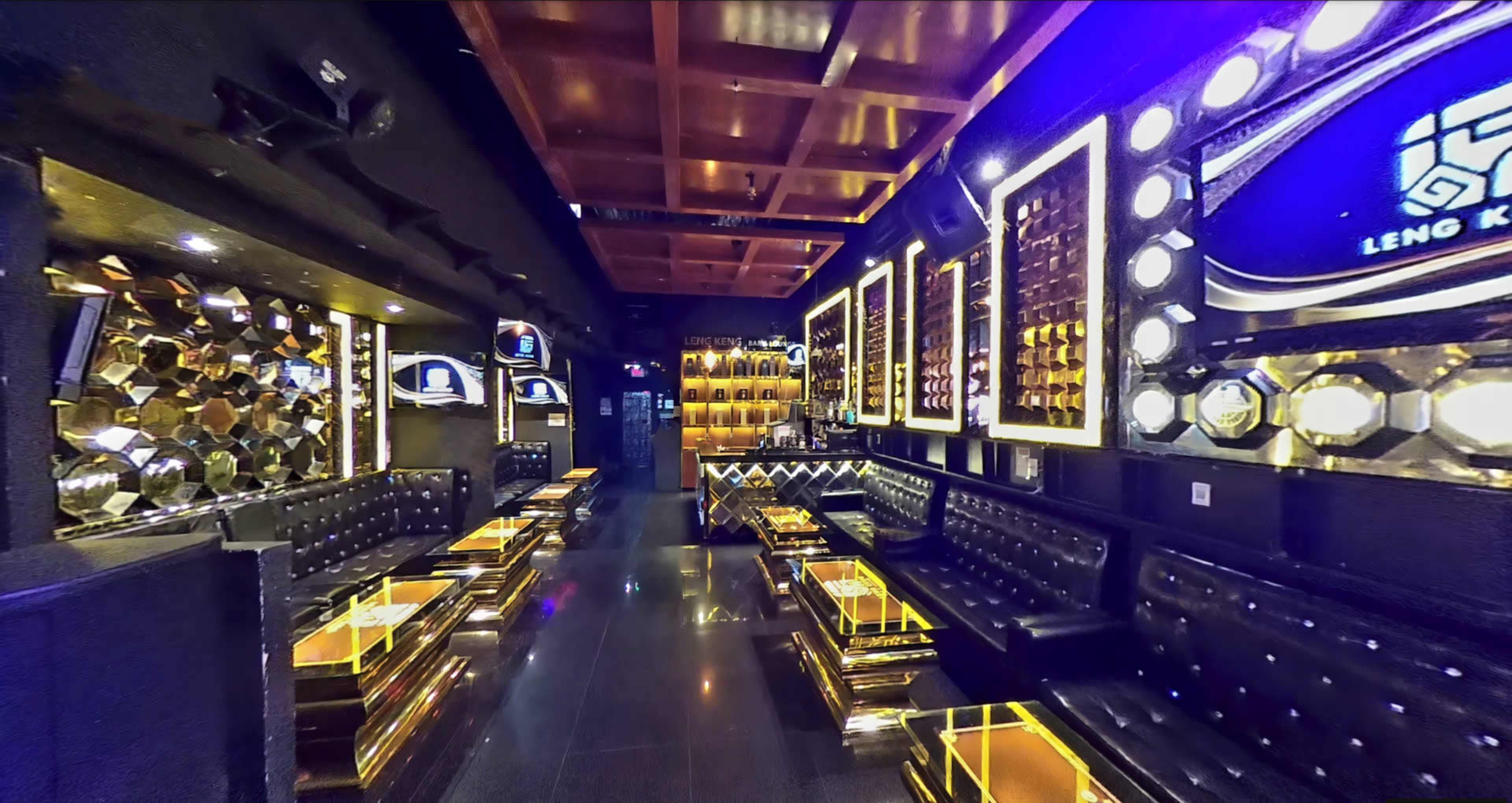 A stylish, modern lounge with gold accents, black seating, and illuminated walls featuring decorative mirrors.