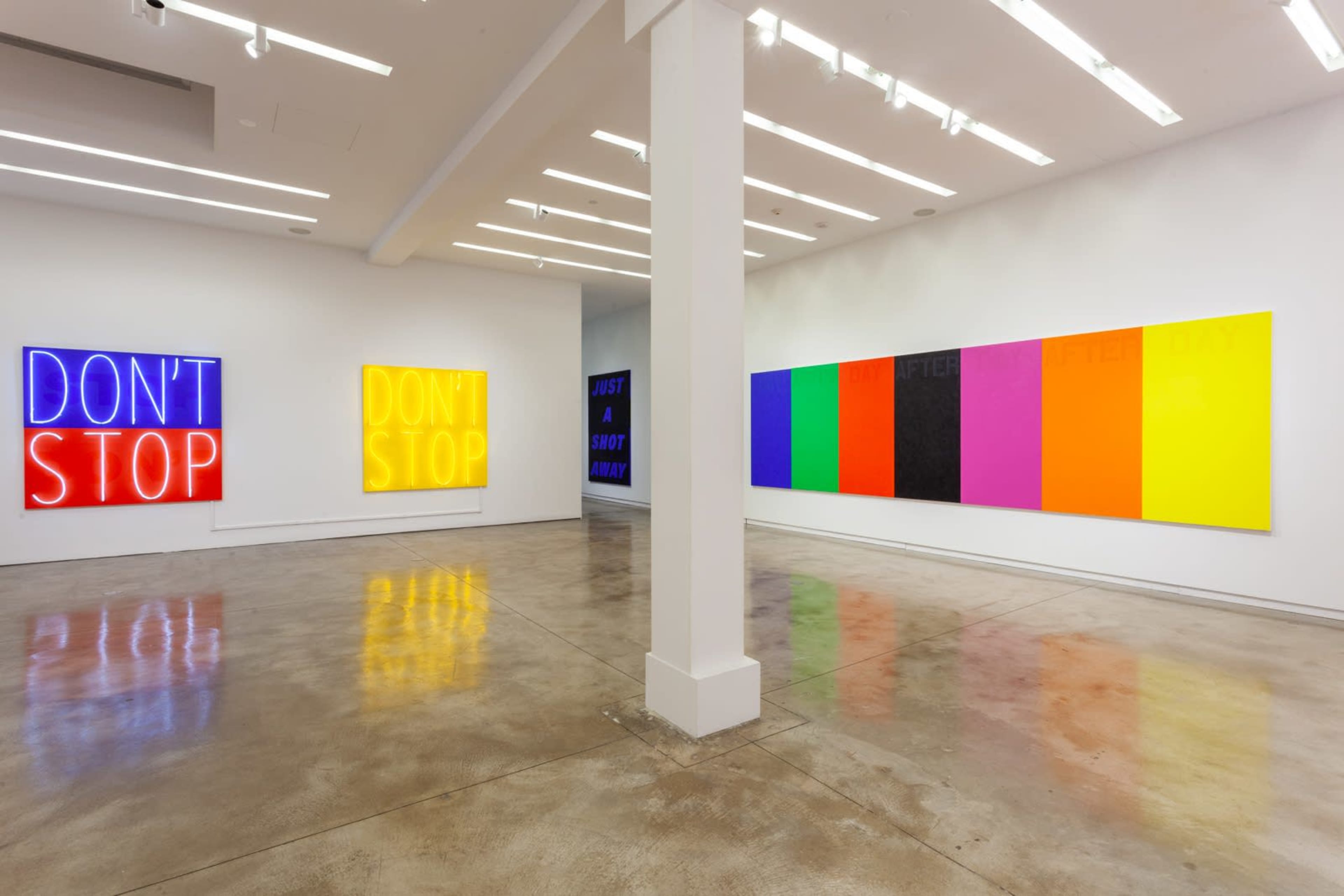 The image shows an art gallery with two brightly lit neon signs reading "DON'T STOP" on one wall and a series of colorful, rectangular canvas artworks on the opposite wall.