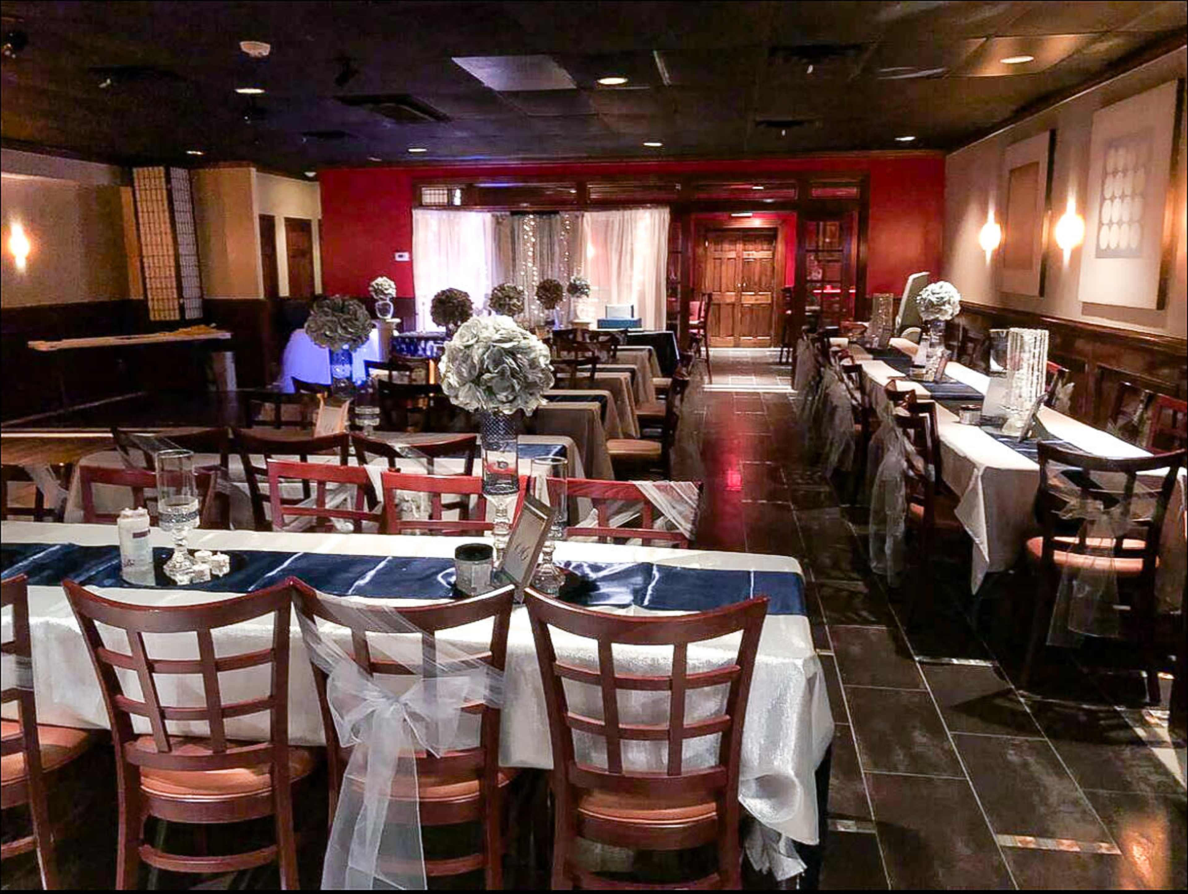 A dining room is set up with tables decorated in white and blue, featuring floral centerpieces and elegant table settings.