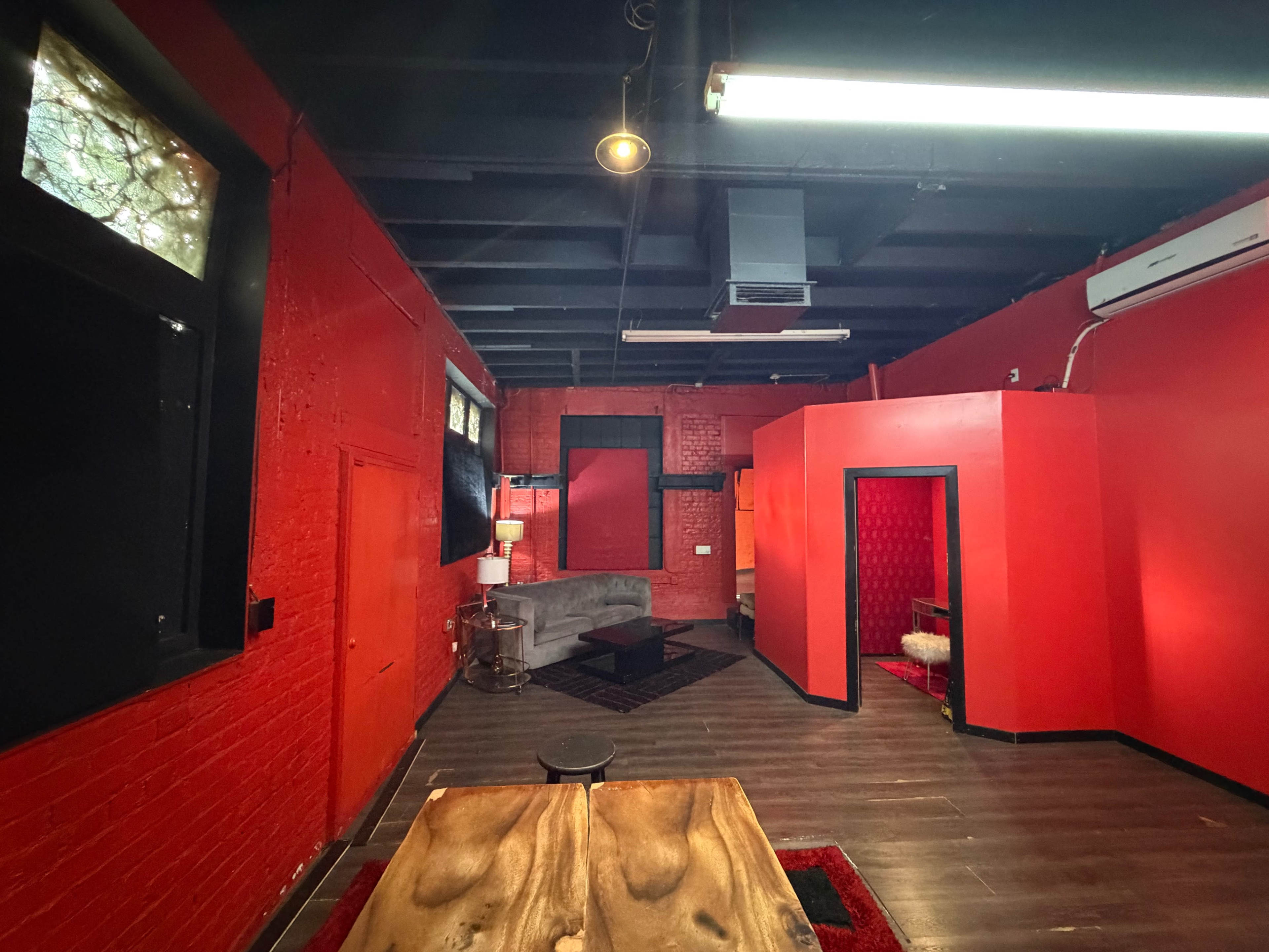 The interior of a room features red walls, a dark wooden table in the foreground, and a gray sofa against one wall.