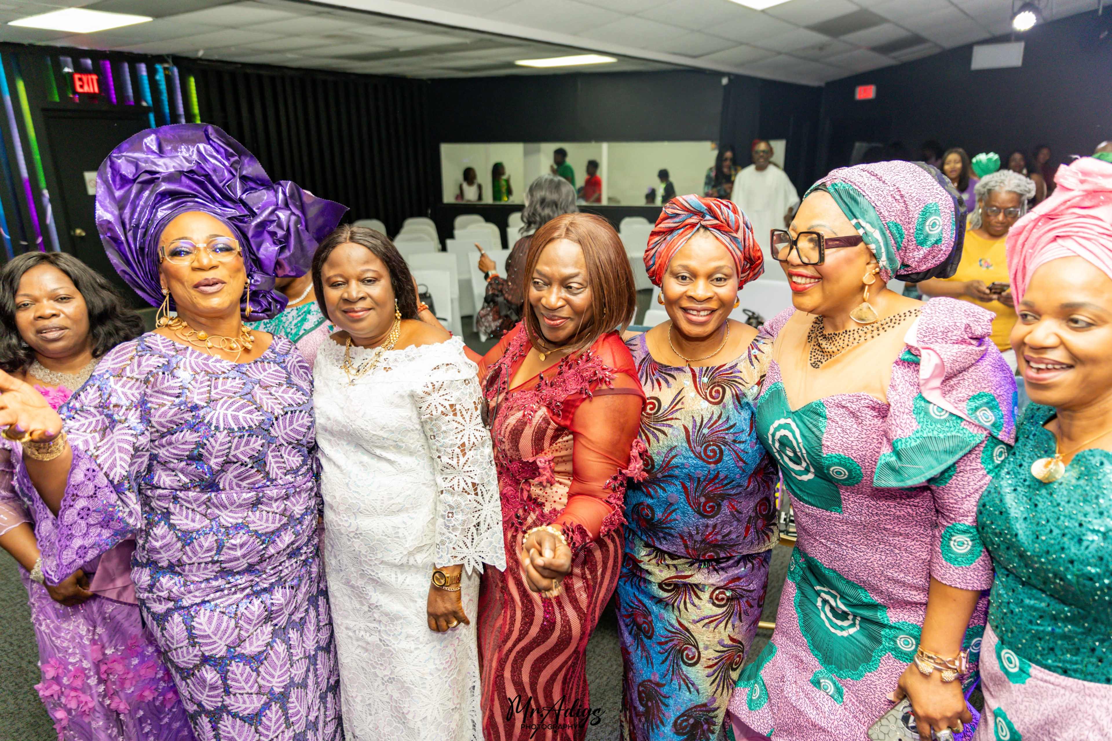 A group of women in colorful dresses celebrate together at an event.