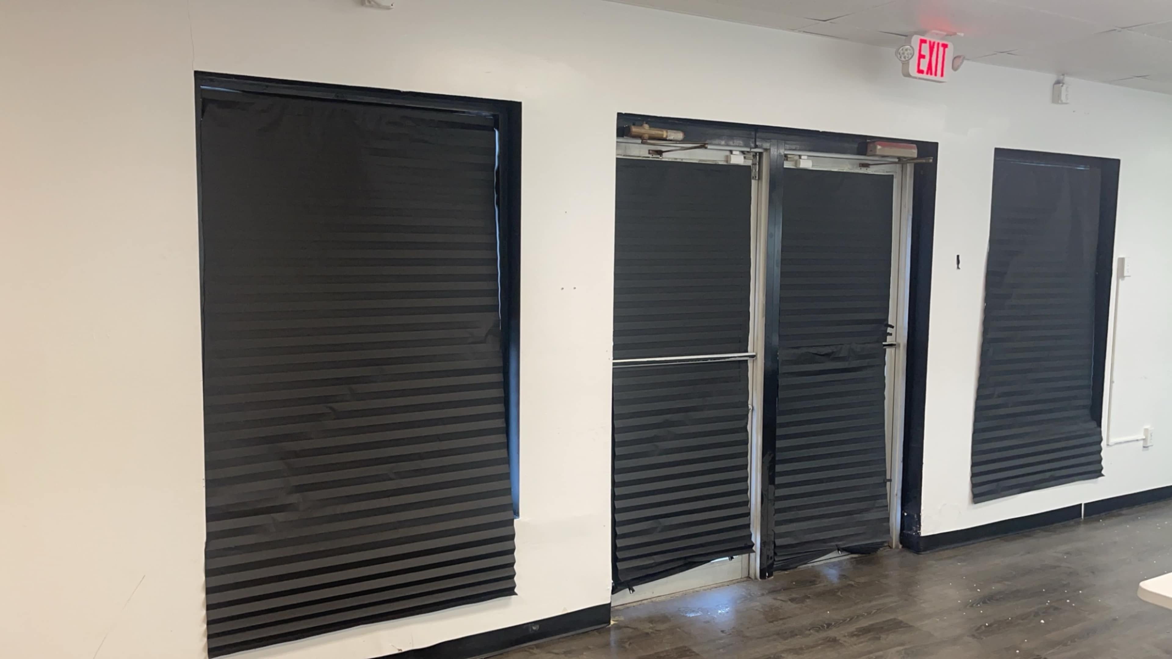 A wall with two covered windows and a set of double doors, all obscured by black window coverings.