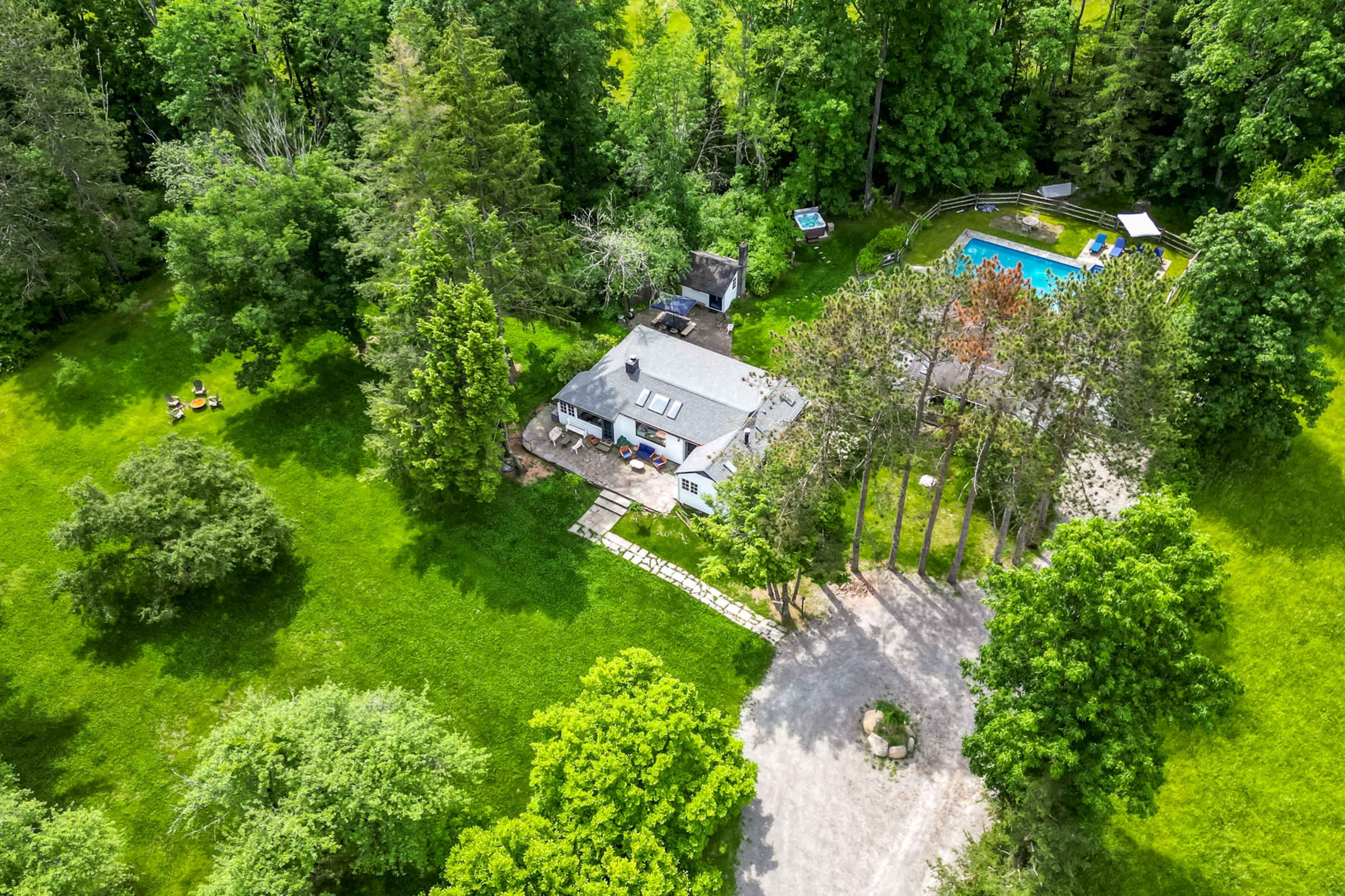 The image shows a large green yard surrounding a house, with a swimming pool and patio area visible nearby.
