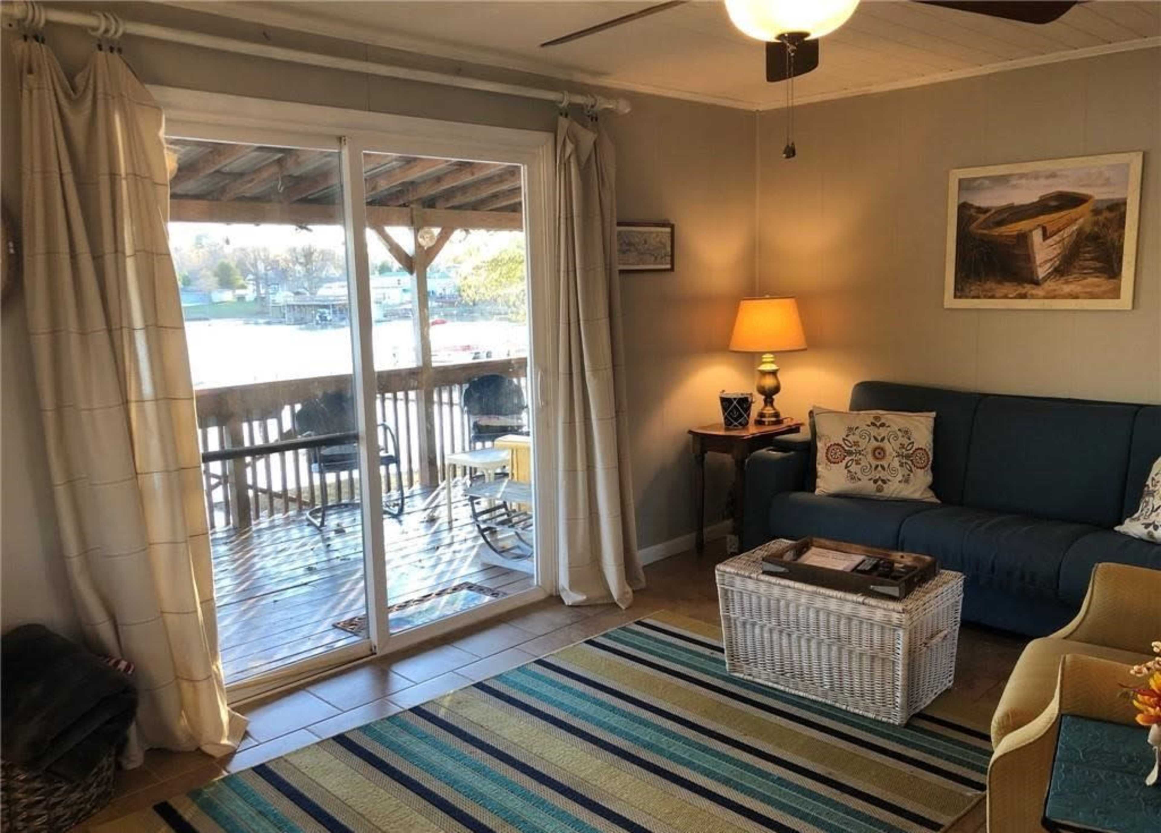 A cozy living room with a blue sofa, a wooden coffee table, and sliding glass doors leading to a deck area.