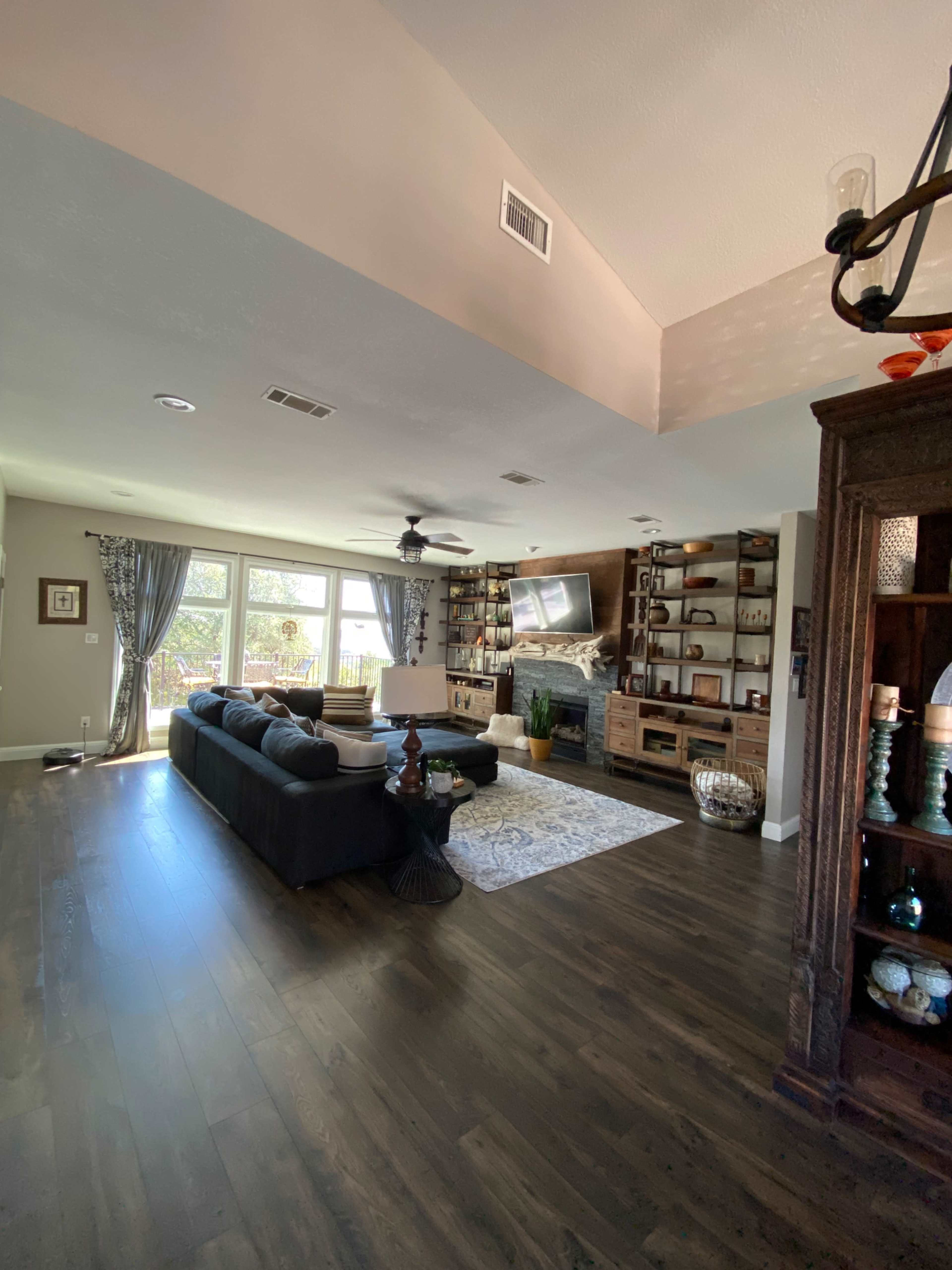 A spacious living room featuring a sectional sofa, a large television, built-in shelves, and large windows that provide natural light.
