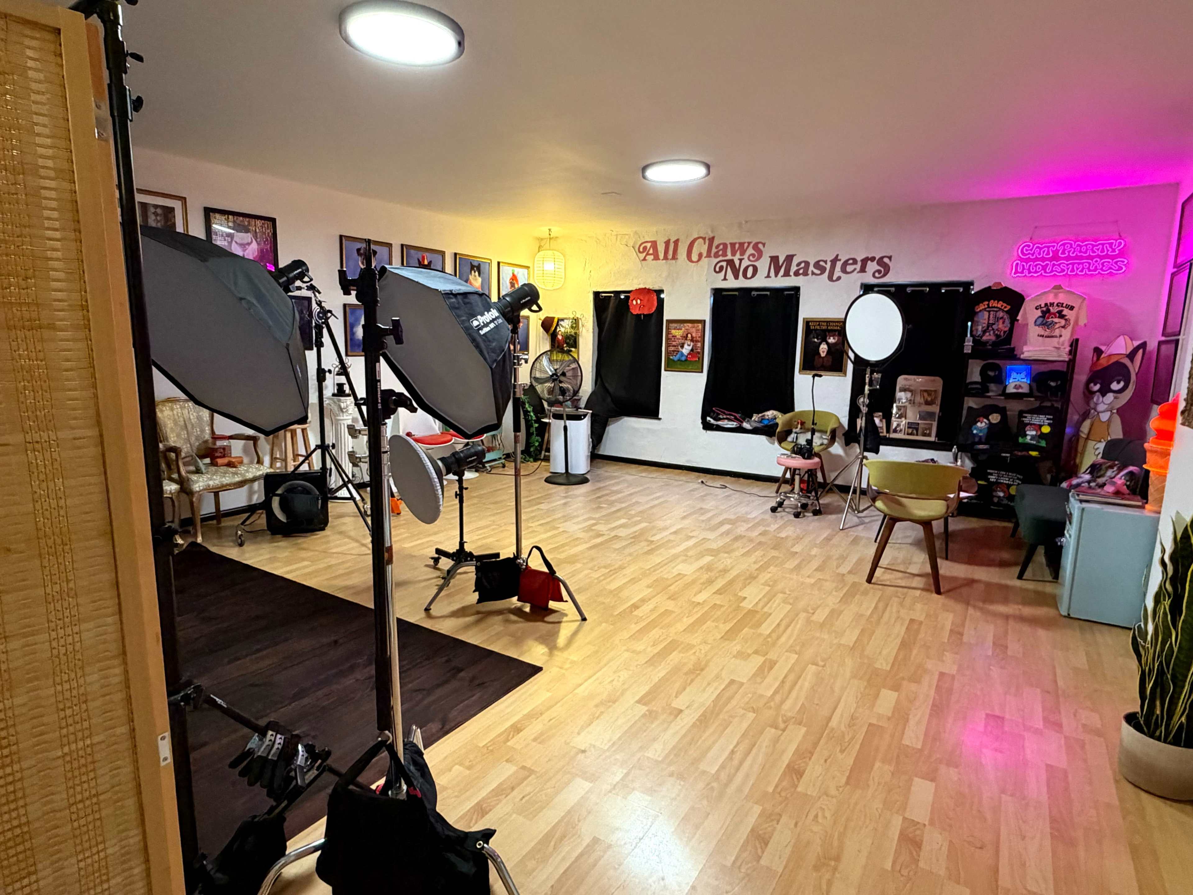 The image shows a spacious room with various lighting equipment, colorful decor, and a mix of furniture, including chairs and wall art.