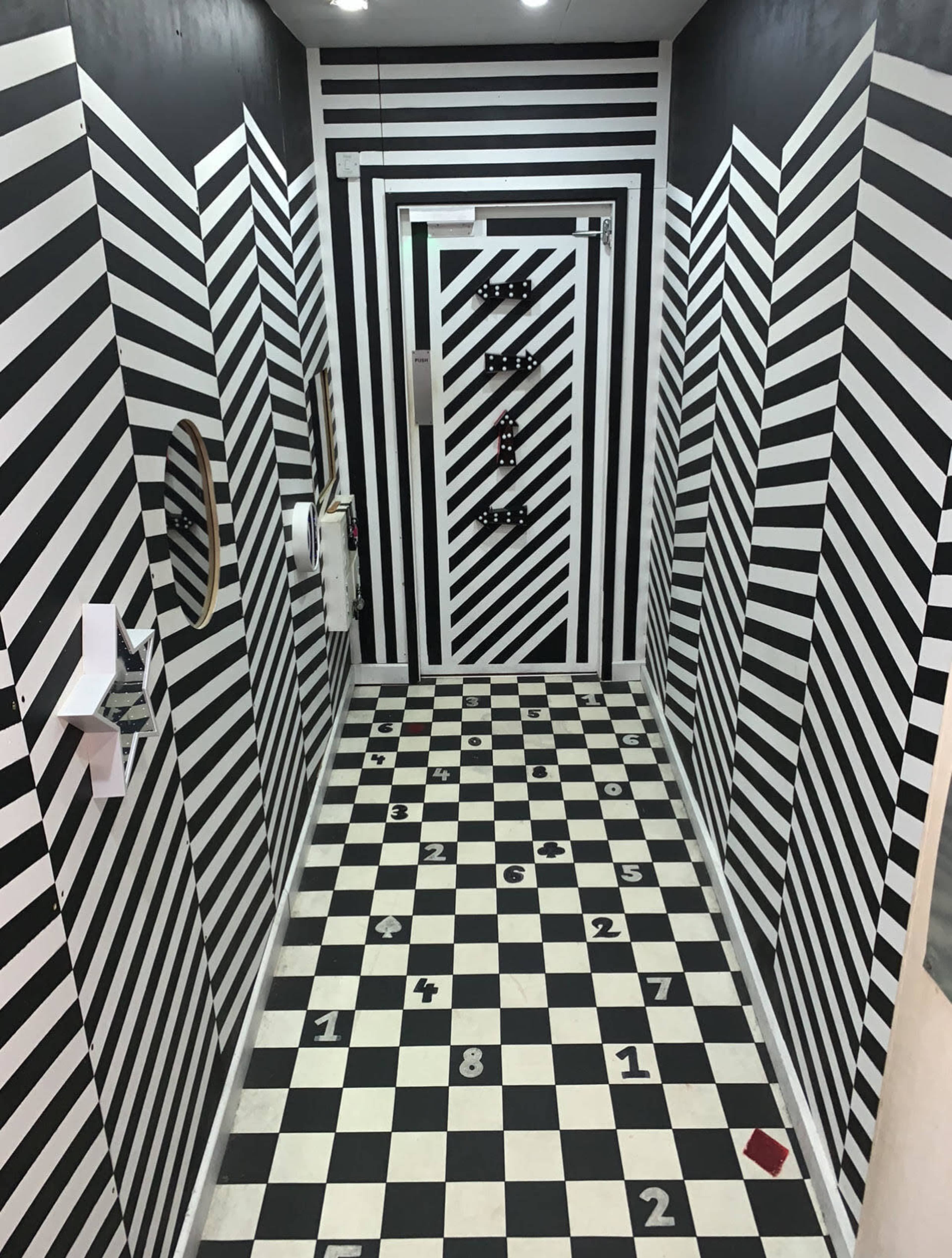 A hallway with a striking black and white striped design on the walls and floor, giving it an optical illusion effect.