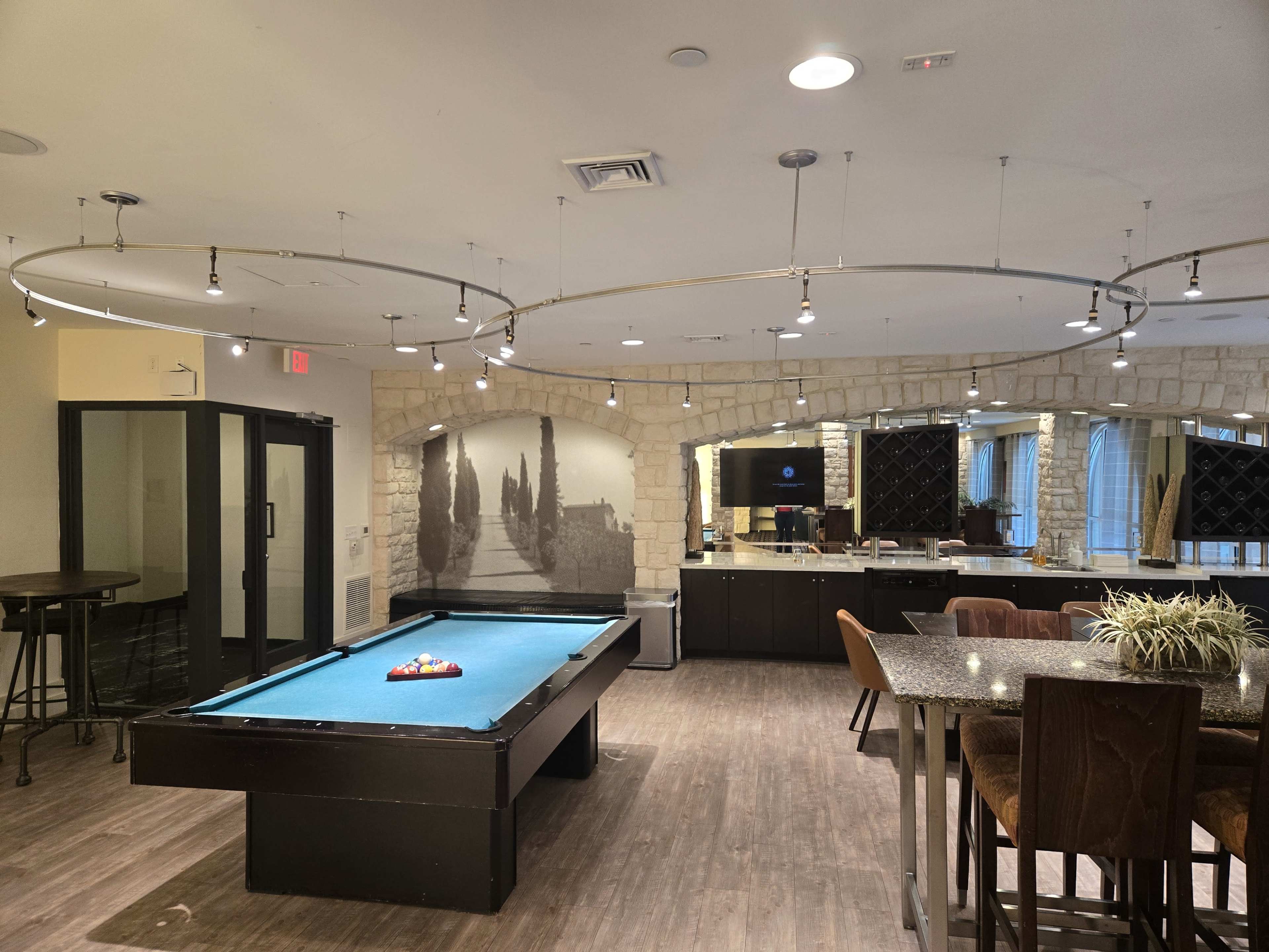 The image shows a room with a pool table, a bar area, and a large mirrored wall reflecting decorative elements.