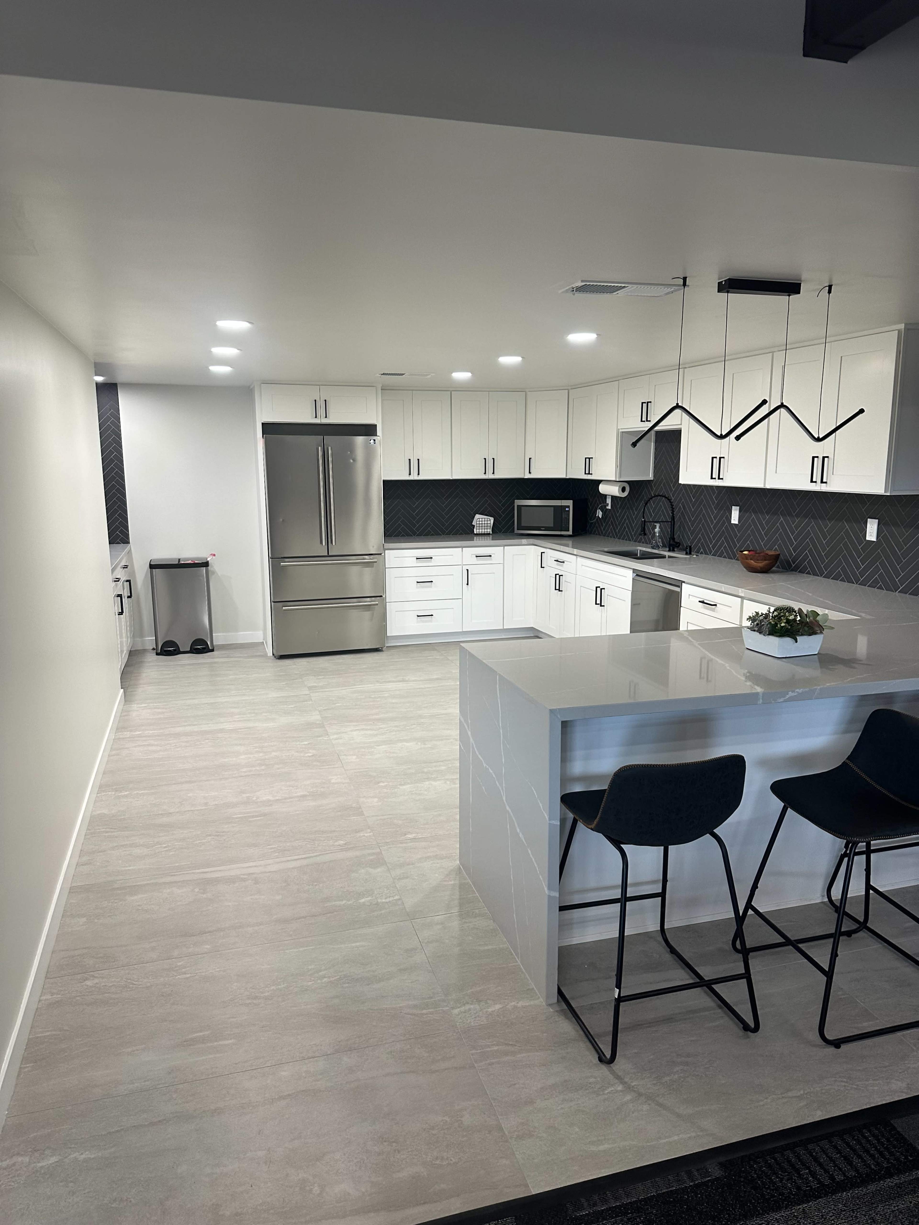 A modern kitchen with white cabinets, stainless steel appliances, and a large island with bar stools.