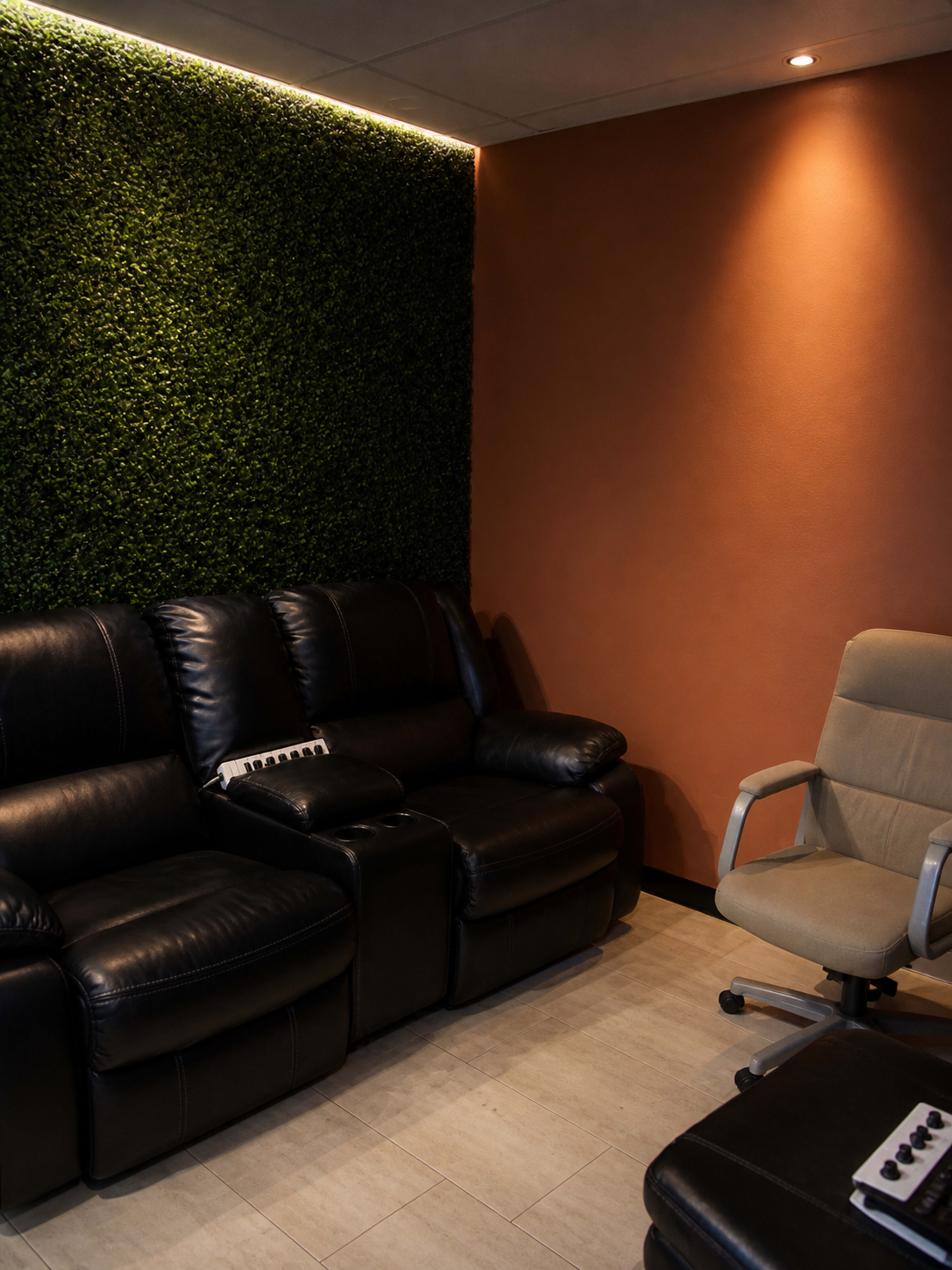 The image shows a cozy room with a black leather sofa and an office chair against a green wall and an orange-painted wall.