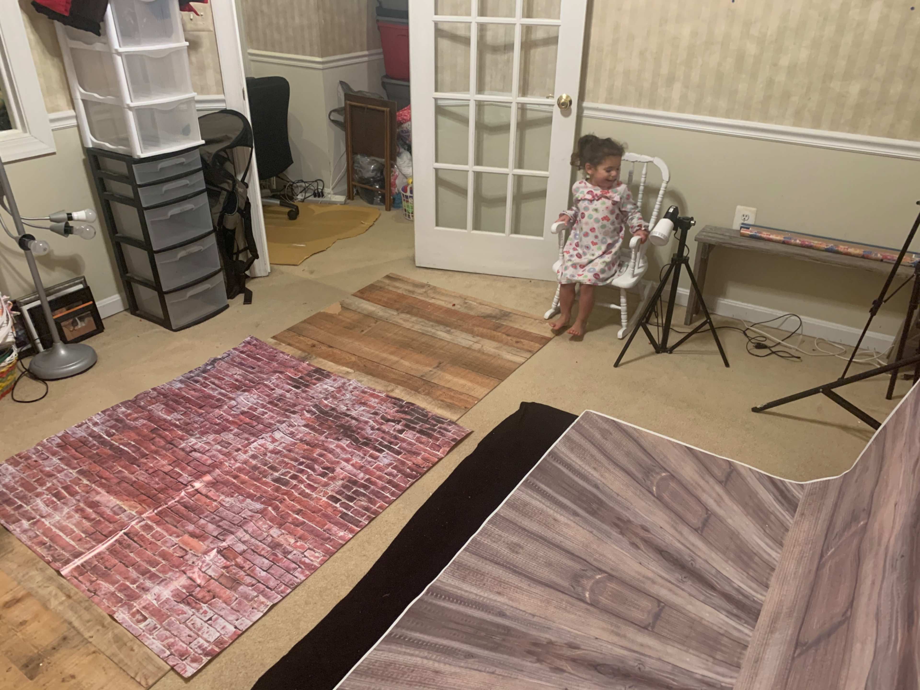 A child stands in a room featuring various textured floor panels, including wood and brick designs, and furniture along the walls.
