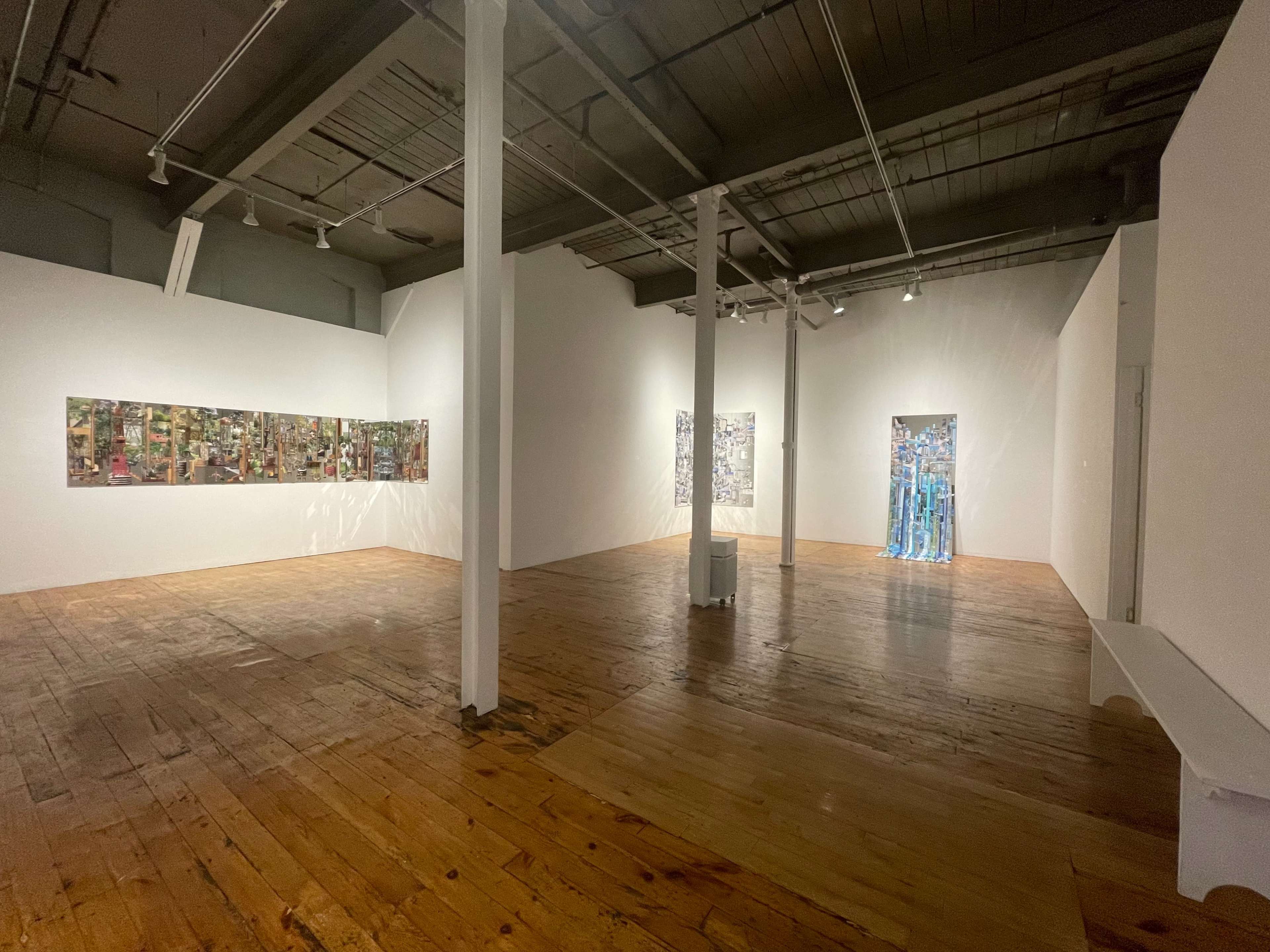 An art gallery with wooden floors, featuring two wall installations and a doorway framed by transparent materials.