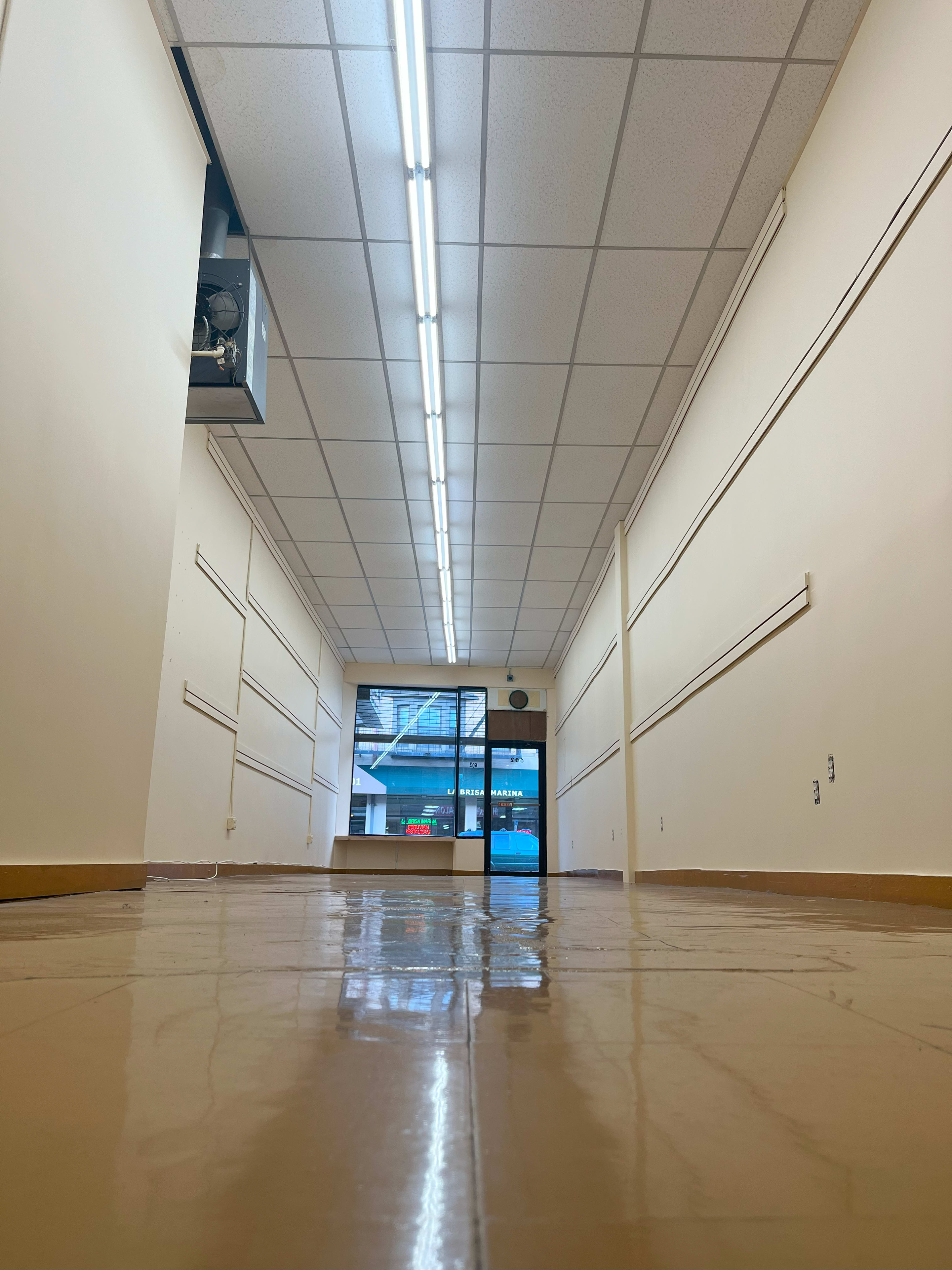 A long, empty hallway with a shiny floor and large glass doors at the far end.