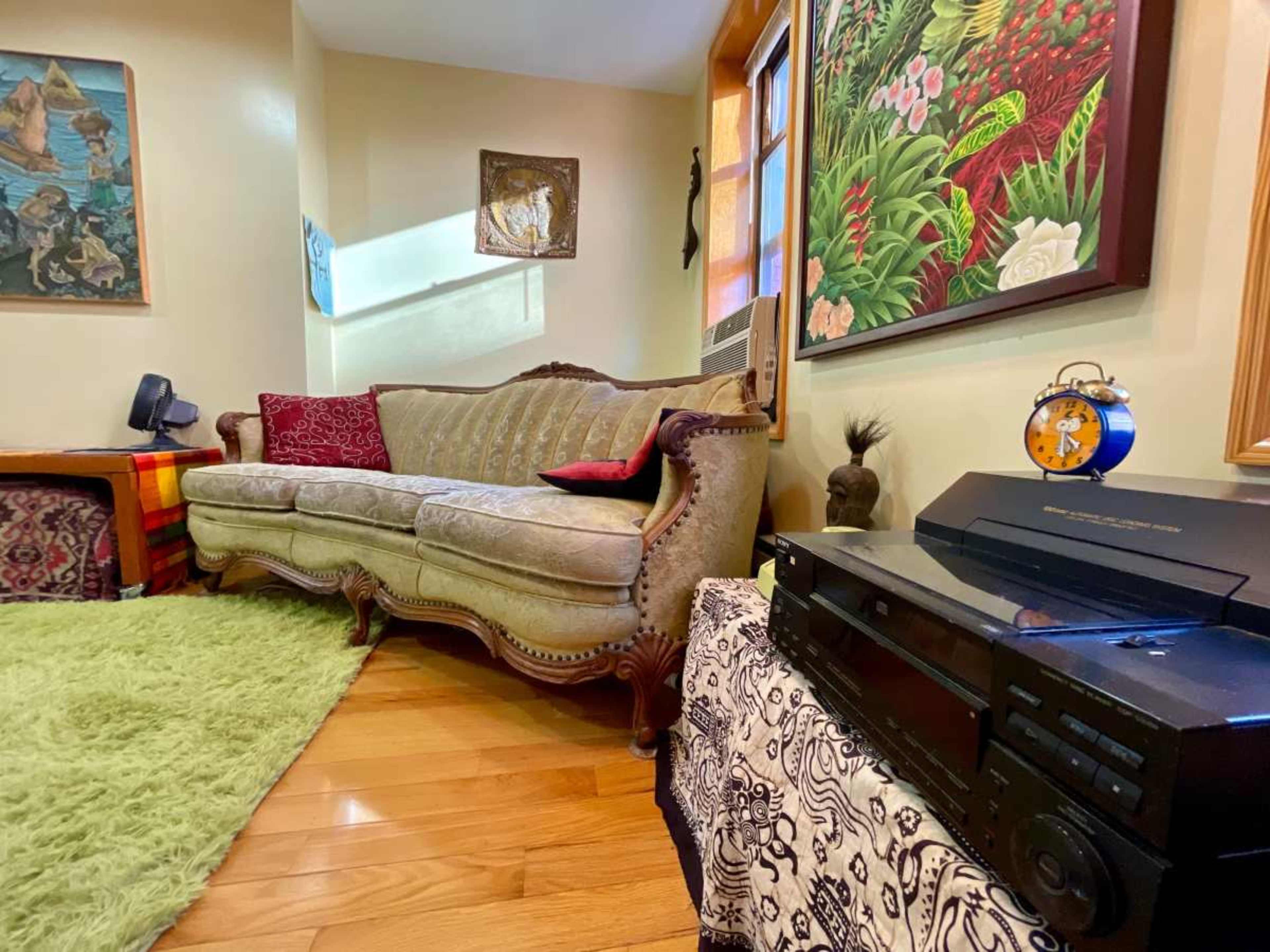 The image depicts a cozy living room with a vintage sofa, a record player, and colorful artwork on the walls.