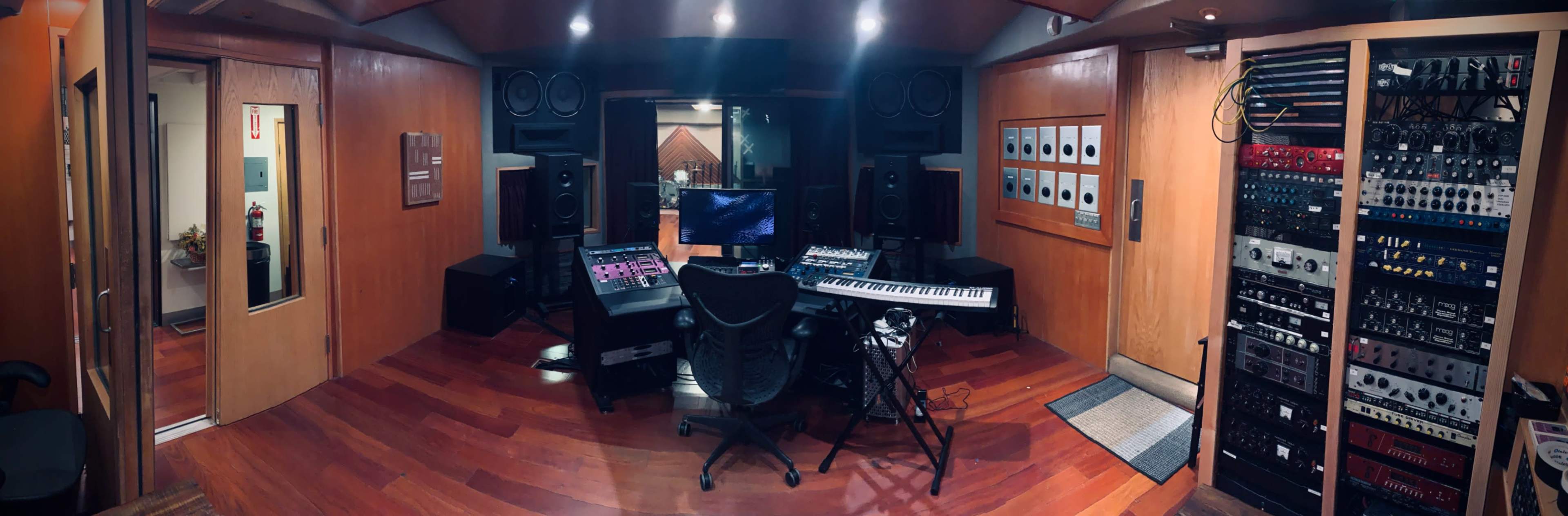 A well-equipped music studio featuring various audio equipment, a keyboard, and a computer setup in a wooden interior.