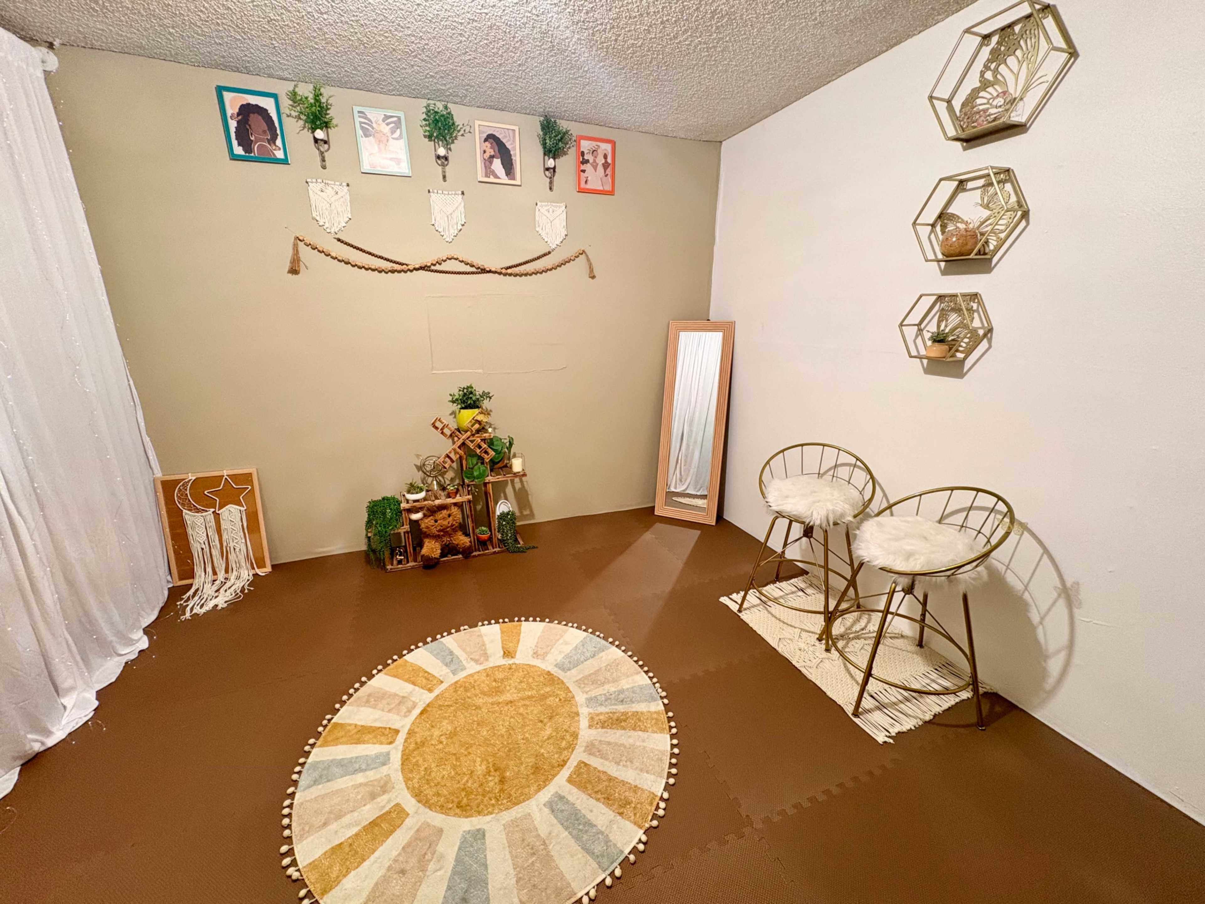 The image shows a minimalist interior room with a circular area rug, two decorative chairs, a full-length mirror, and wall art featuring portraits and plants.