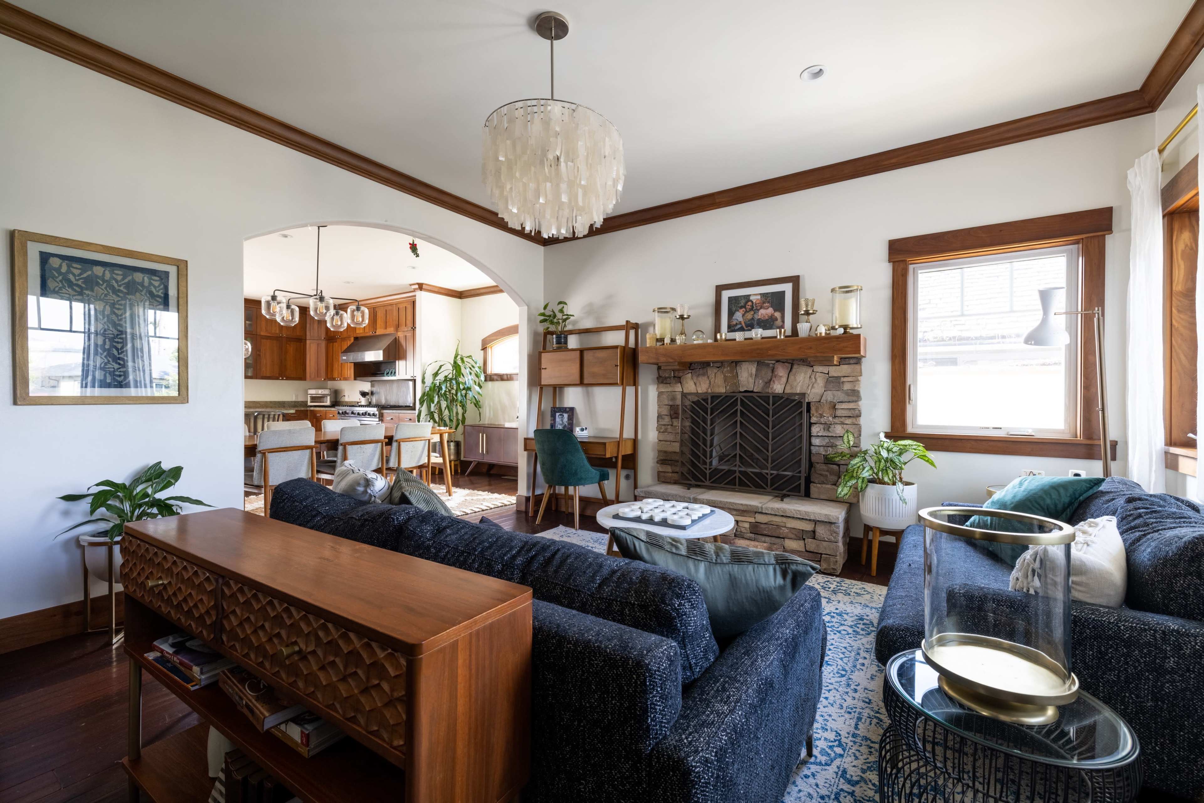 A living room with a stone fireplace, two dark sofas, and a dining area visible in the background.