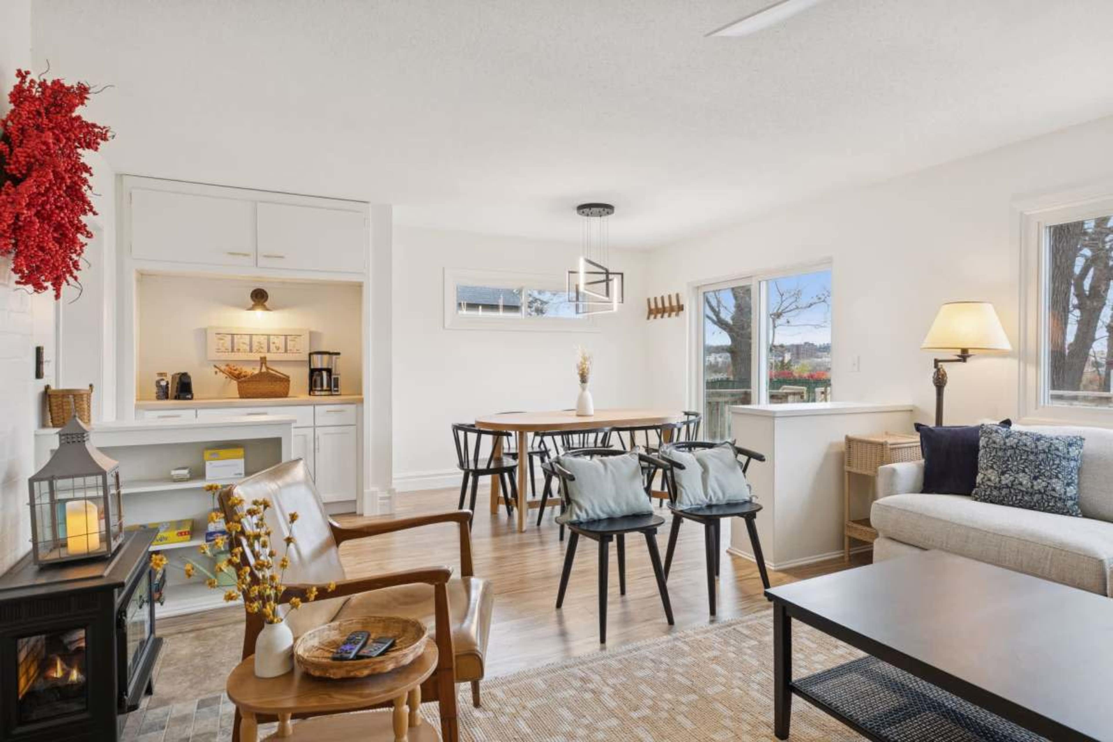 The image shows a bright and modern living area featuring a sofa, dining table, and decorative elements like a wreath and a lantern.
