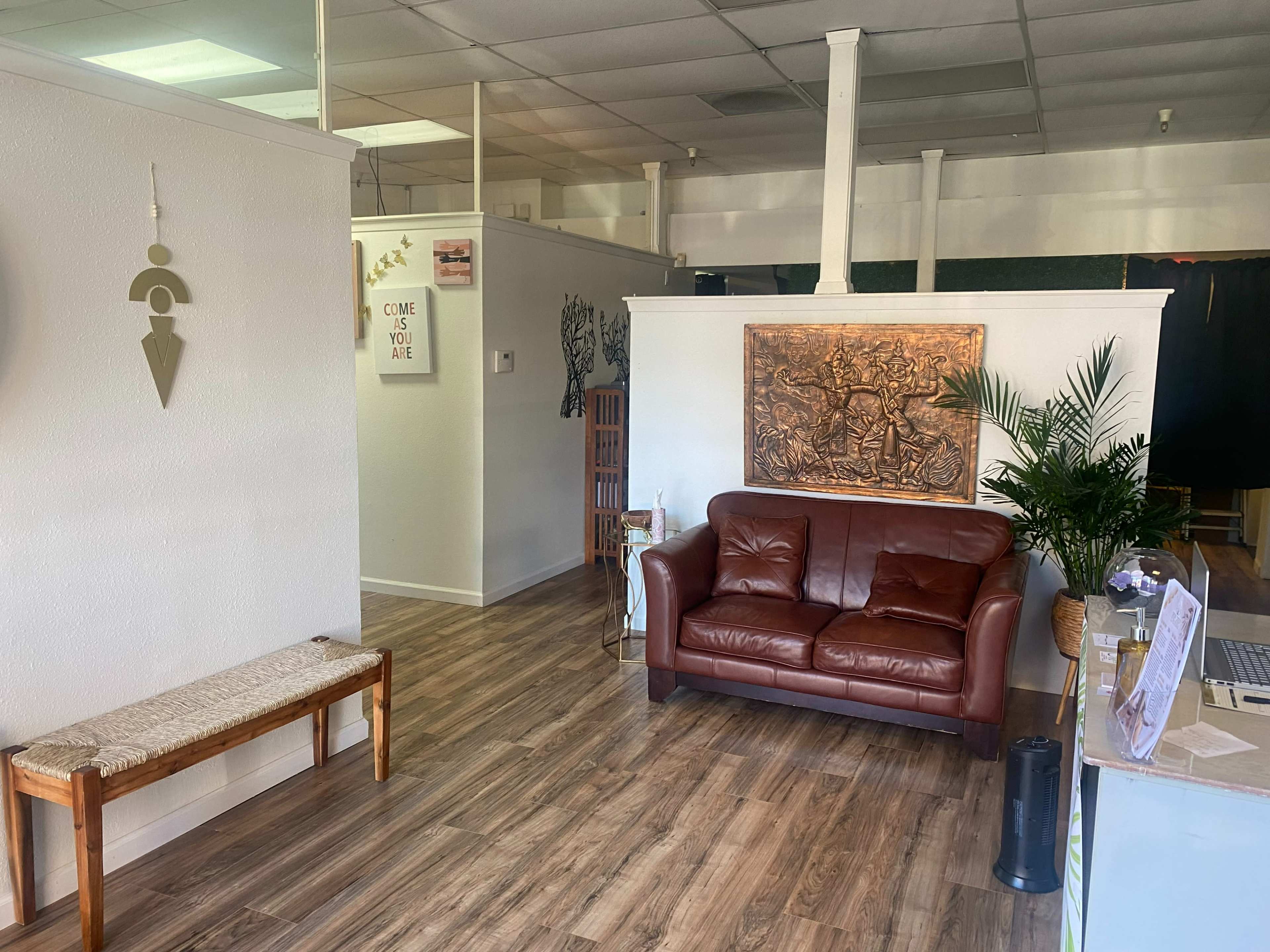 A spacious, well-lit interior with a leather couch, decorative wall art, and wooden flooring.