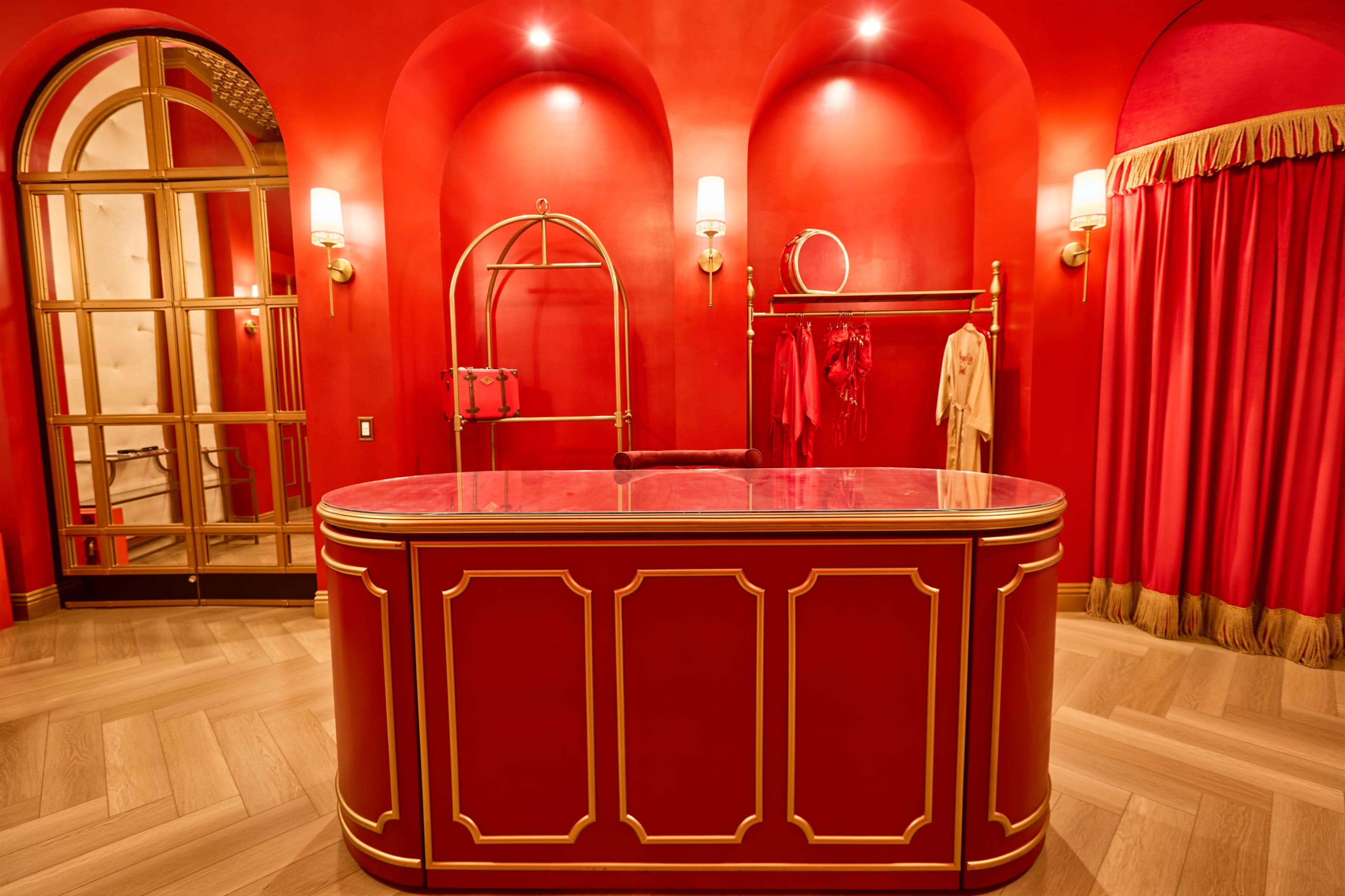 The scene features a red-themed reception area with a glossy red counter, gold accents, and elegant clothing racks displaying red garments.