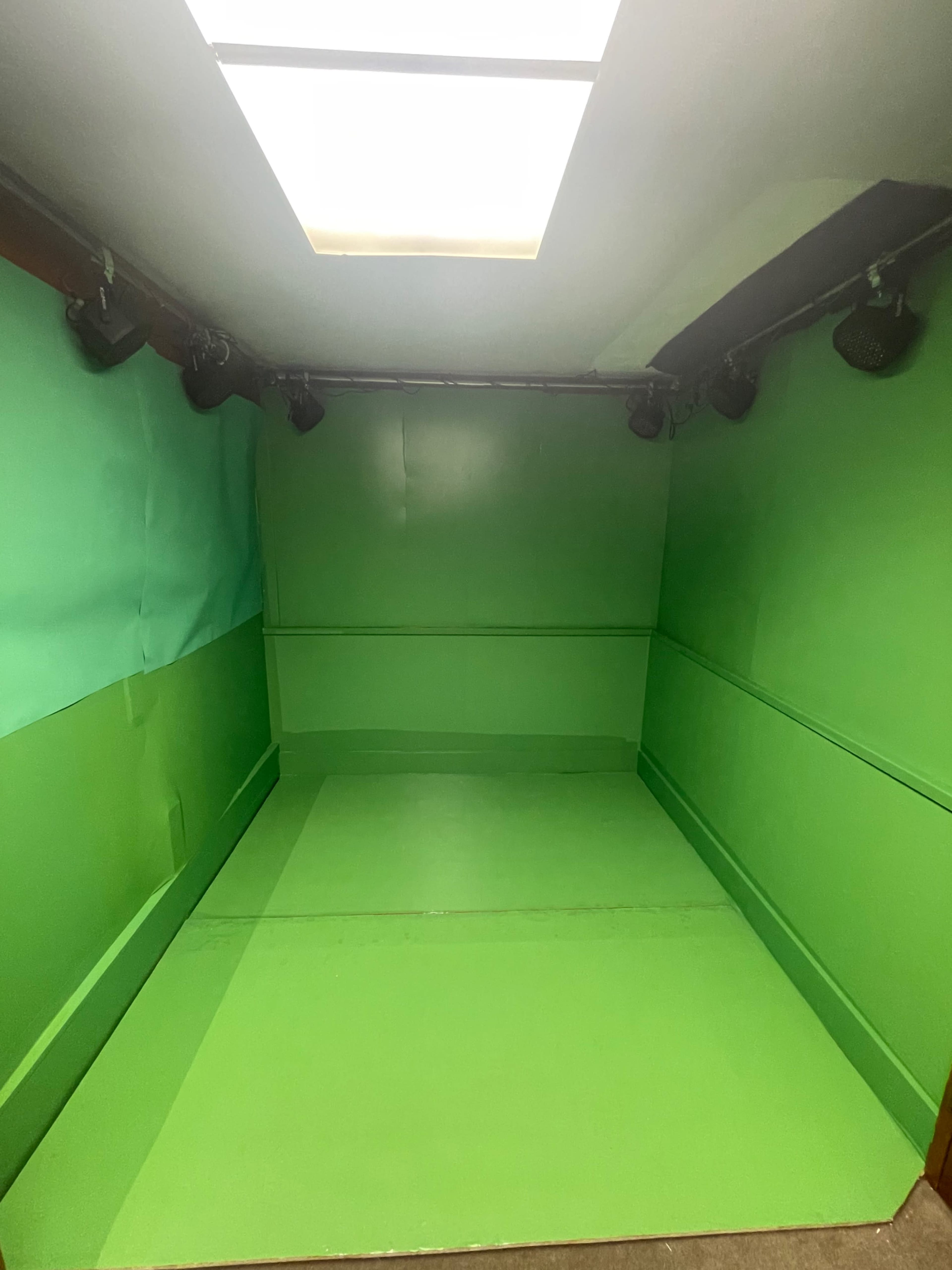 A room with green walls, a green floor, and ceiling lights.