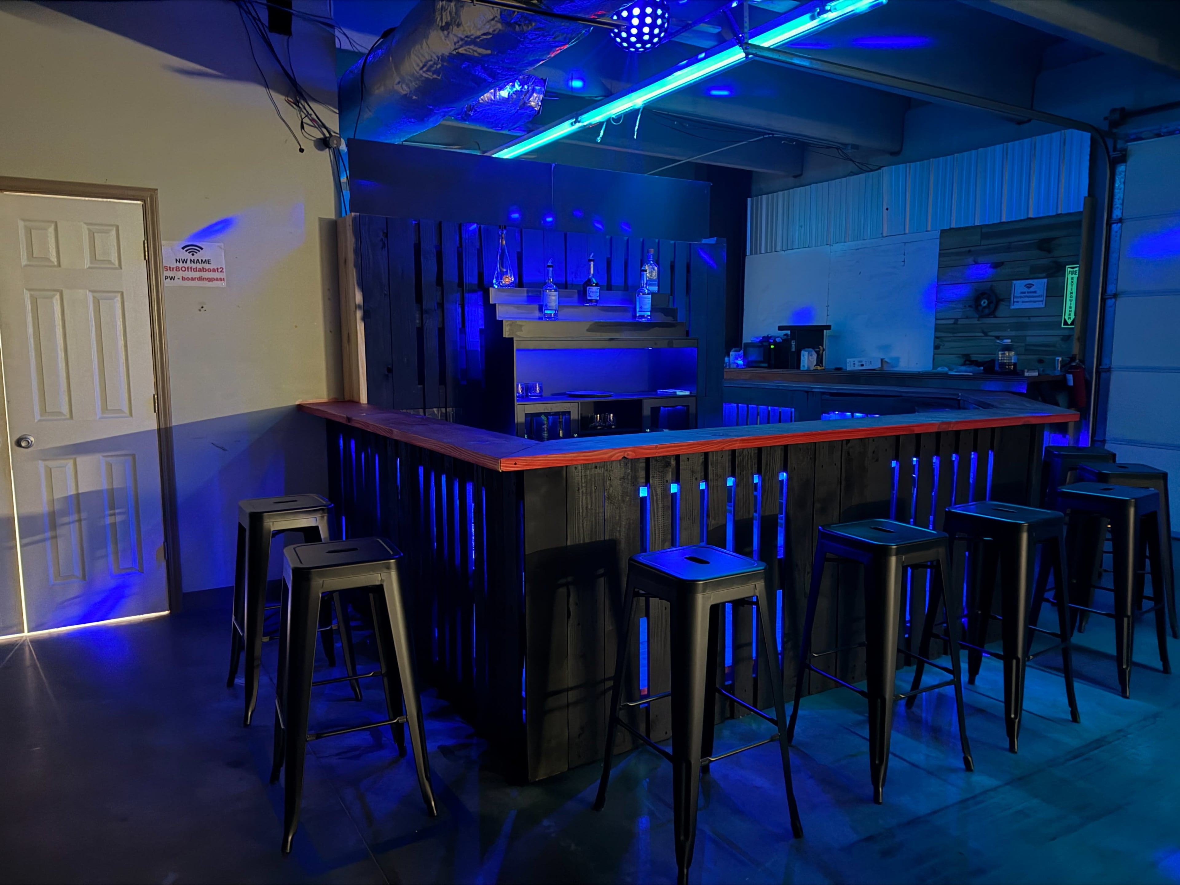 The image shows a modern bar area with black stools and blue LED lighting.