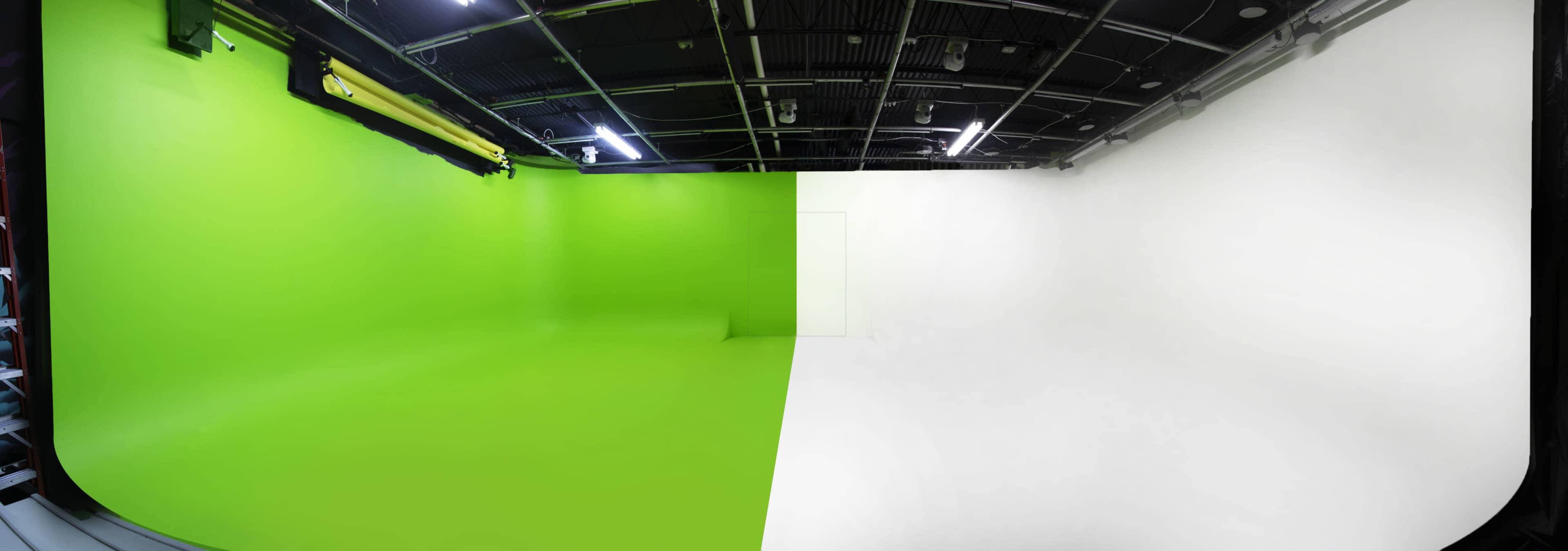 The image shows a studio space divided into two sections, with one side featuring a bright green backdrop and the other side a plain white wall.