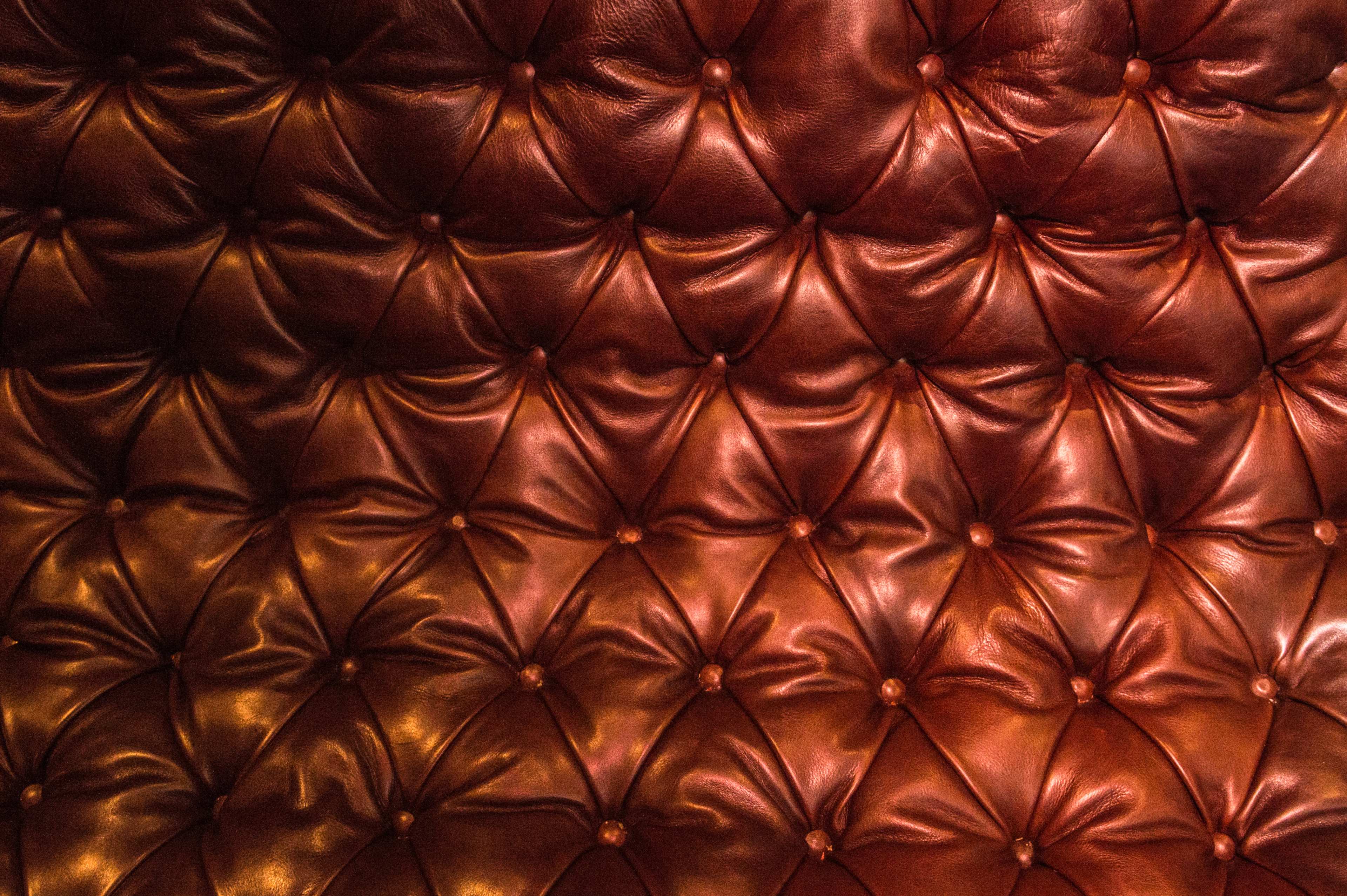 A close-up of a tufted leather wall in rich, dark tones.