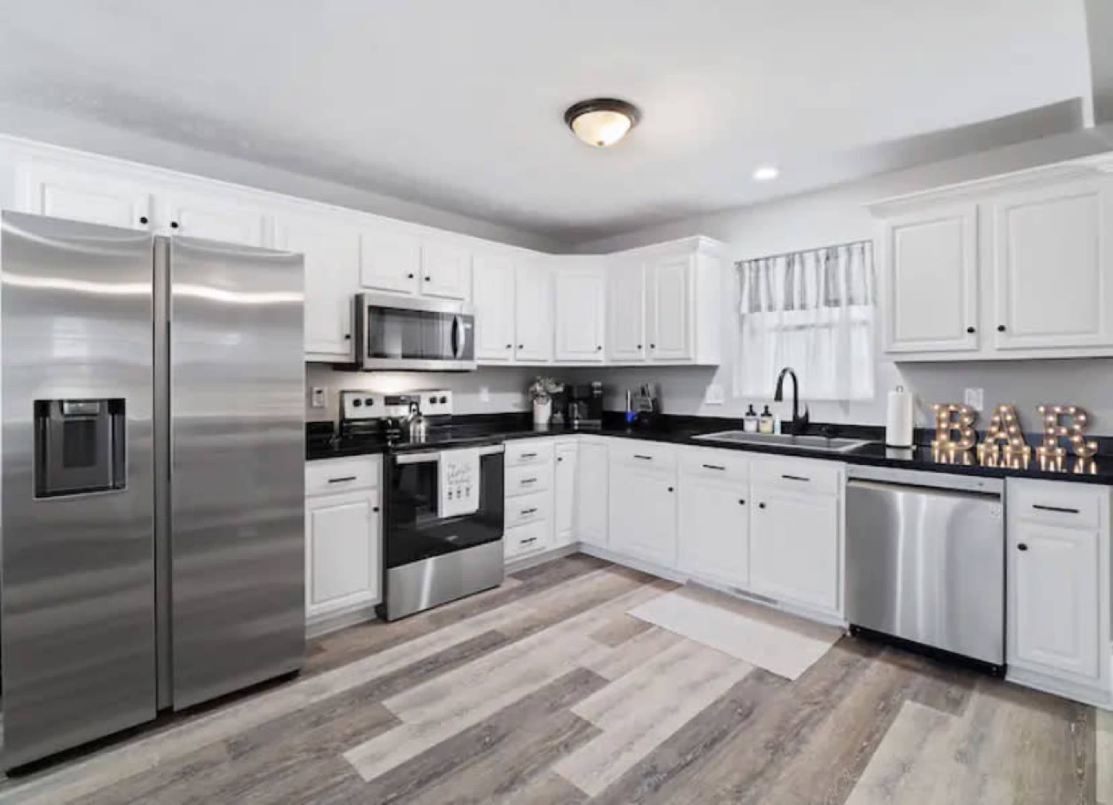 A modern kitchen with white cabinets, stainless steel appliances, and a dark countertop.