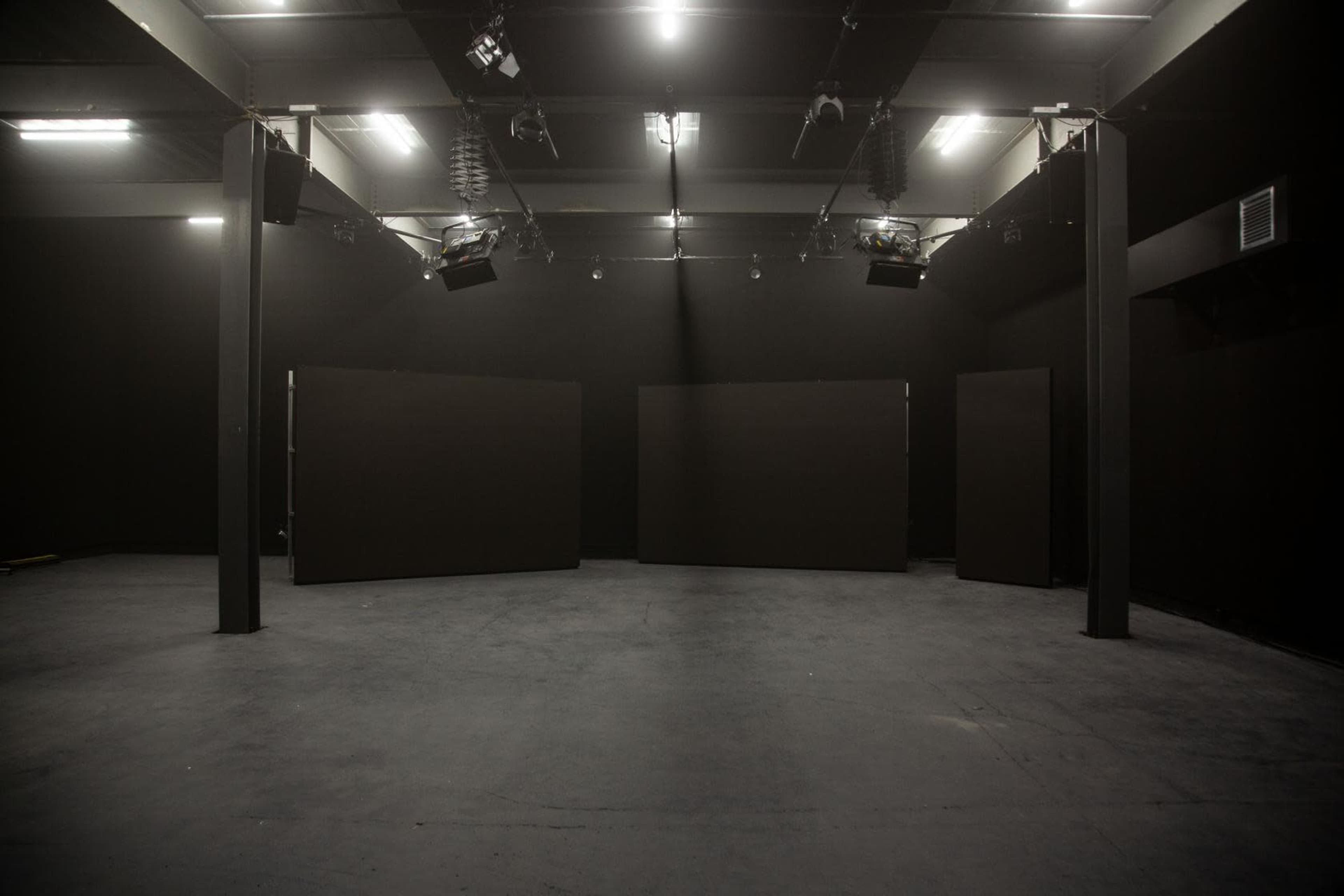 A dimly lit room with black walls and several large, dark panels arranged in the center.