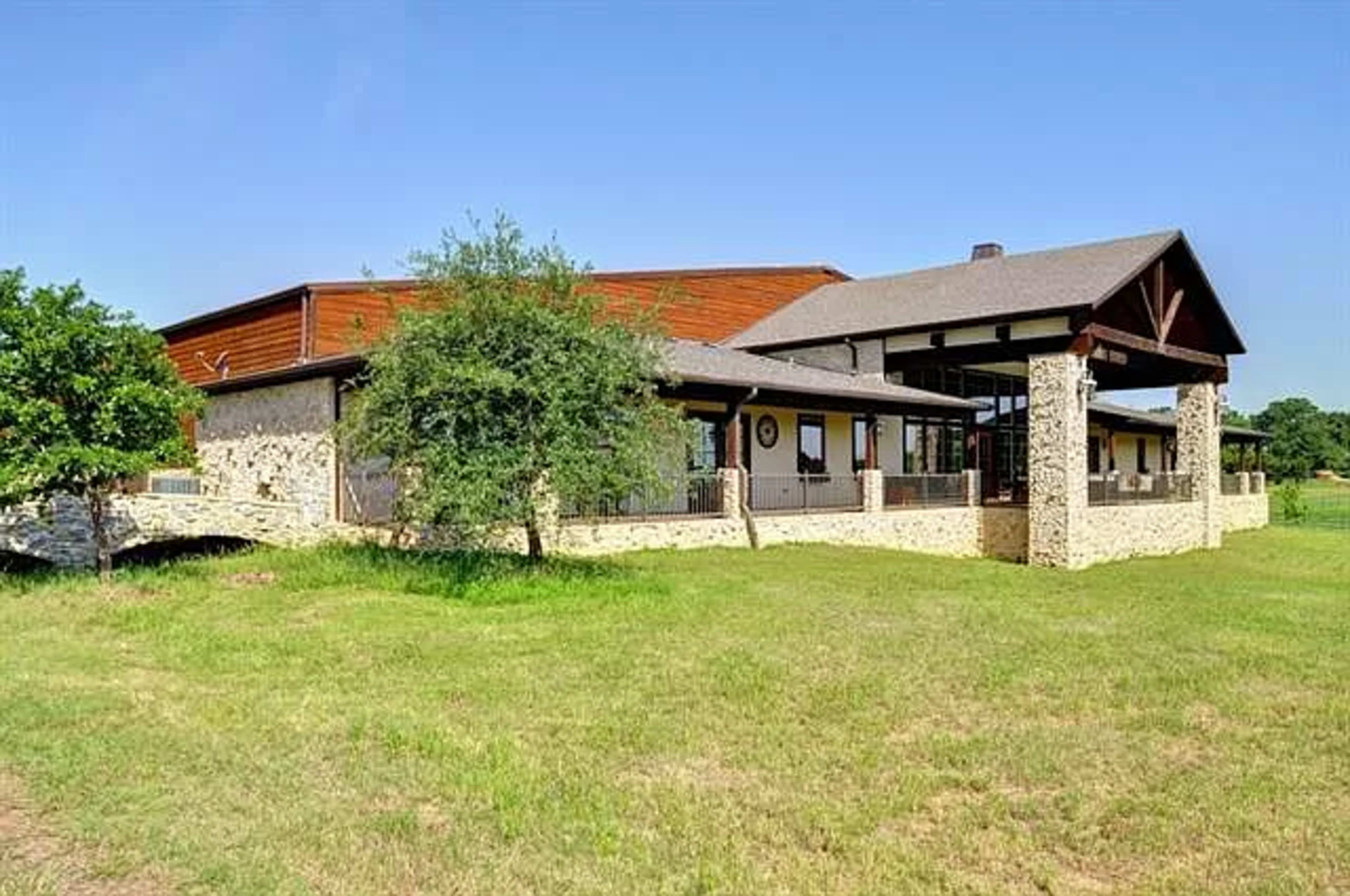 A modern stone and wood building with a sloped roof set on a grassy landscape.