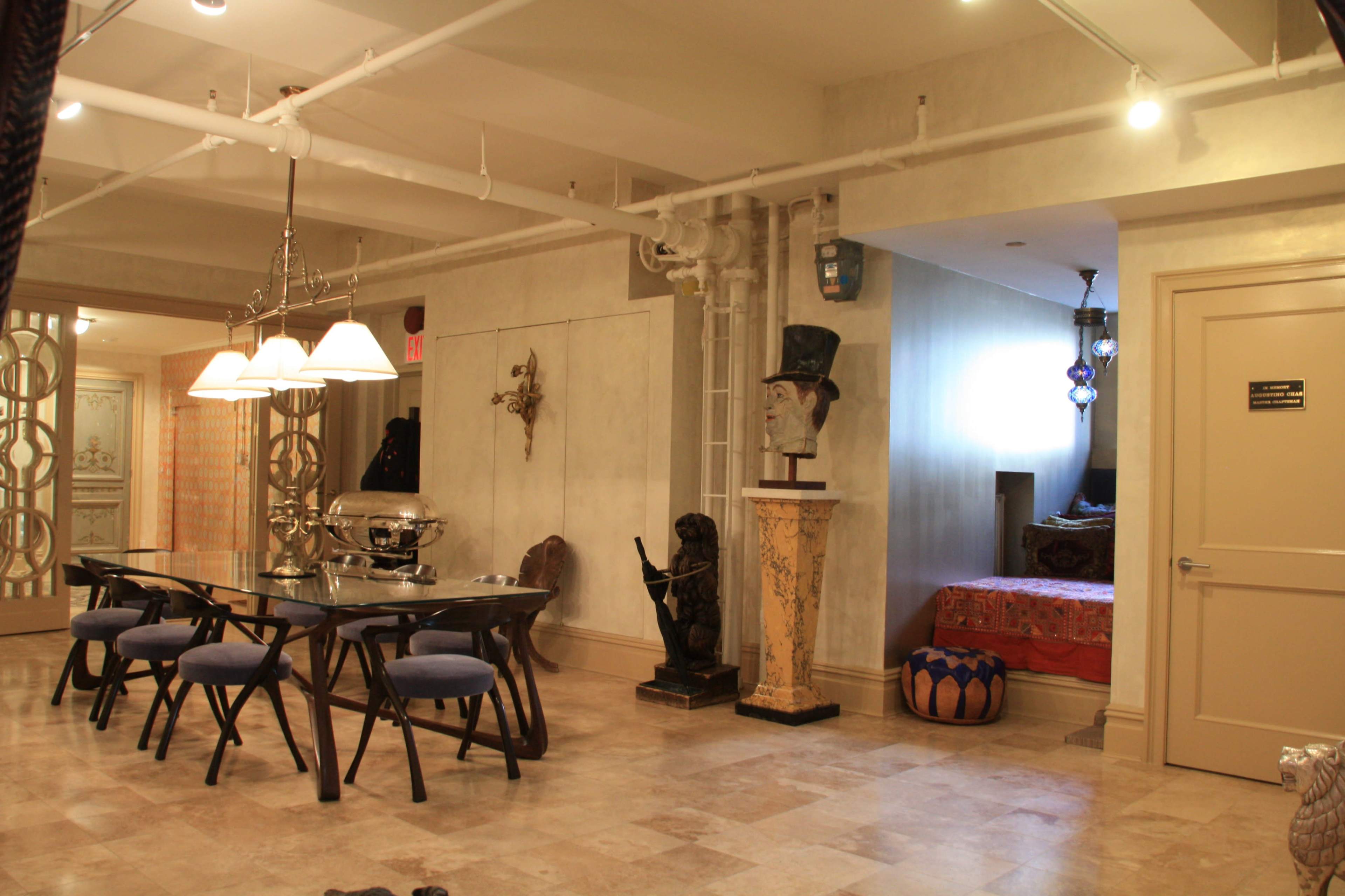 The image shows a spacious room with a dining table, decorative items, and a partially visible bedroom area in the background.