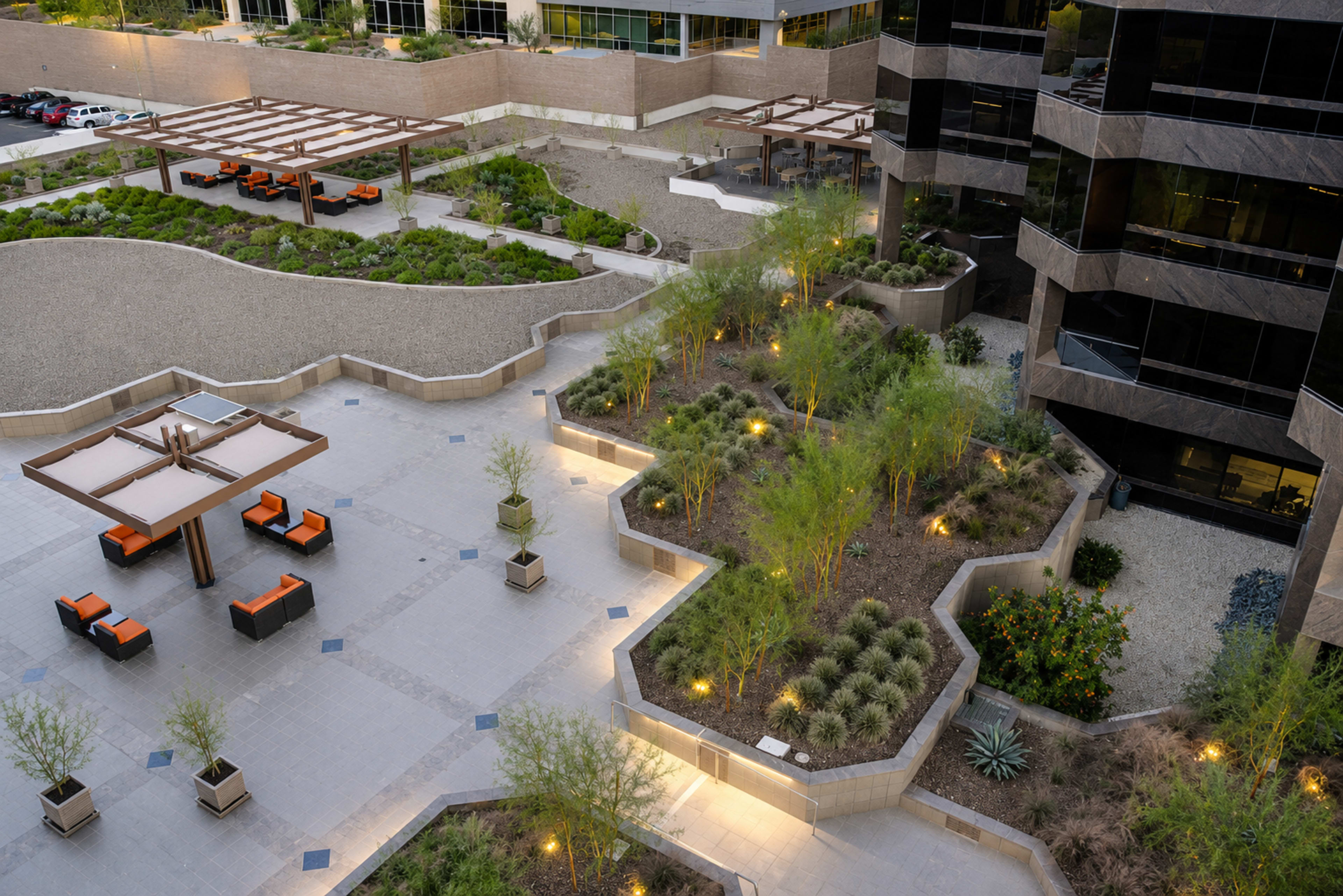The image shows a modern outdoor courtyard featuring landscaped areas with desert plants, seating arrangements, and pathways amid a commercial building backdrop.