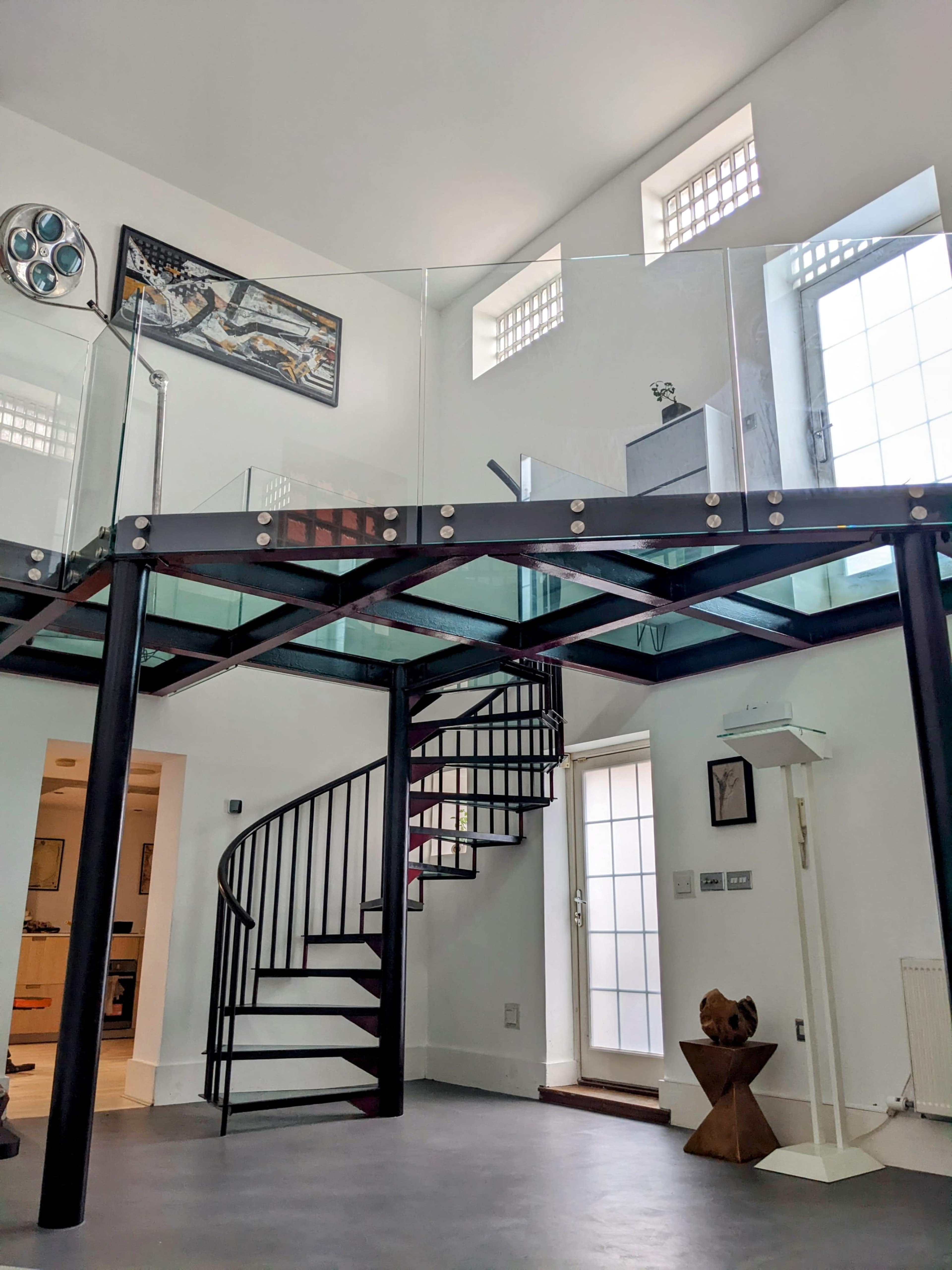 A modern interior space featuring a spiral staircase leading to a glass-walled upper level.