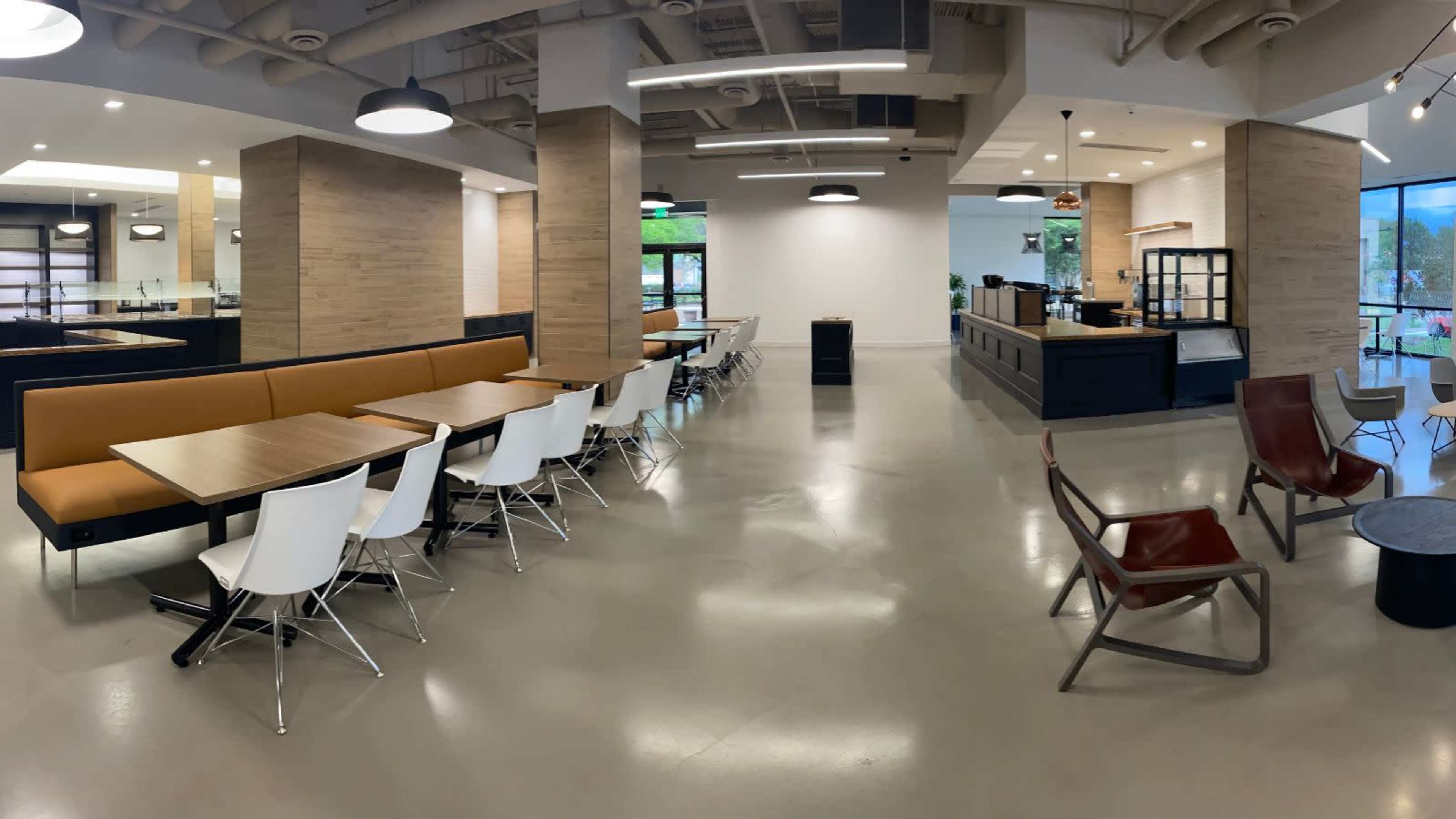 A modern cafeteria with a mix of brown and white seating arrangements and a counter area in the background.