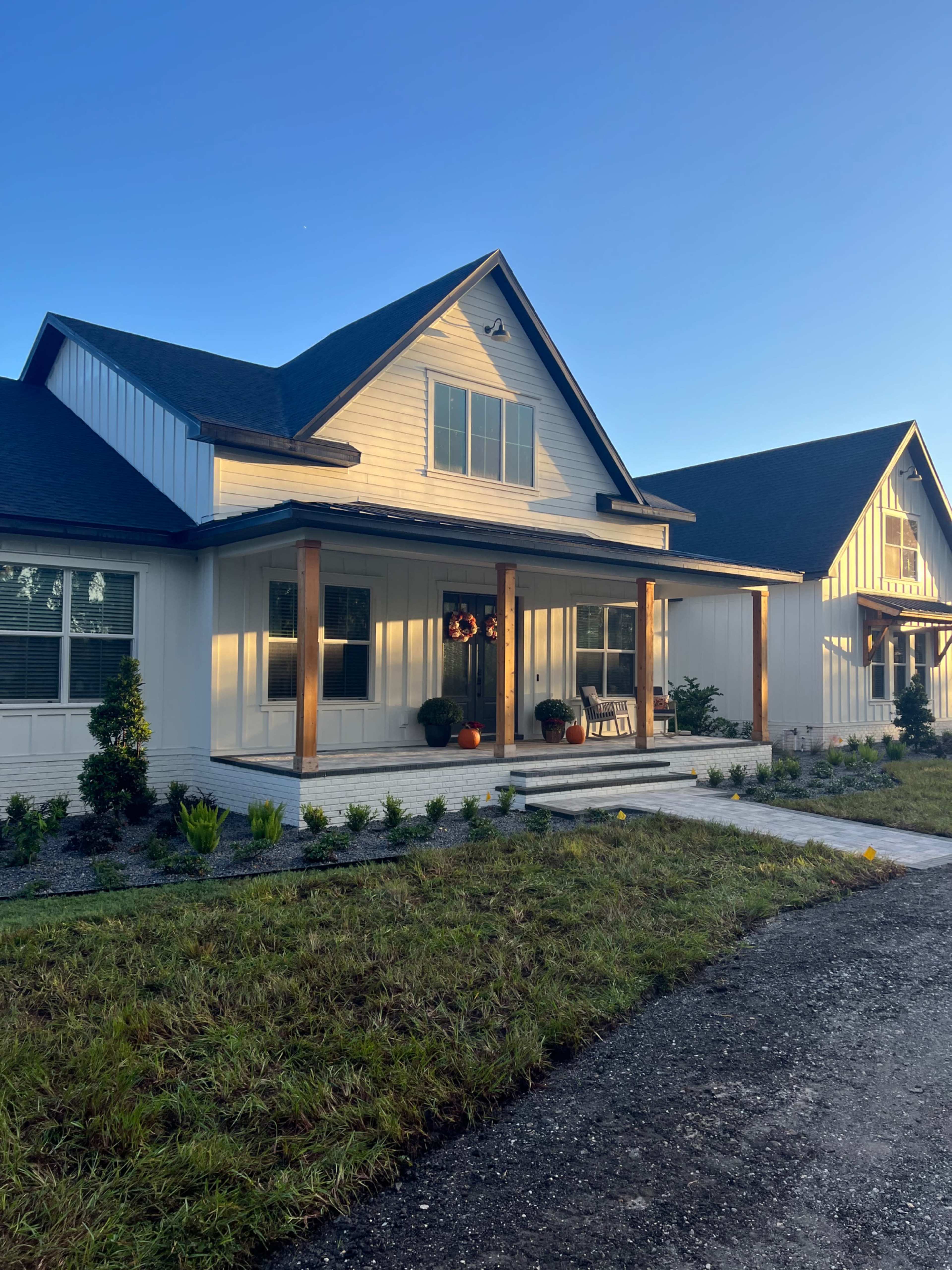 A modern single-family home with a porch and landscaped yard, featuring a mix of siding and a gabled roof.