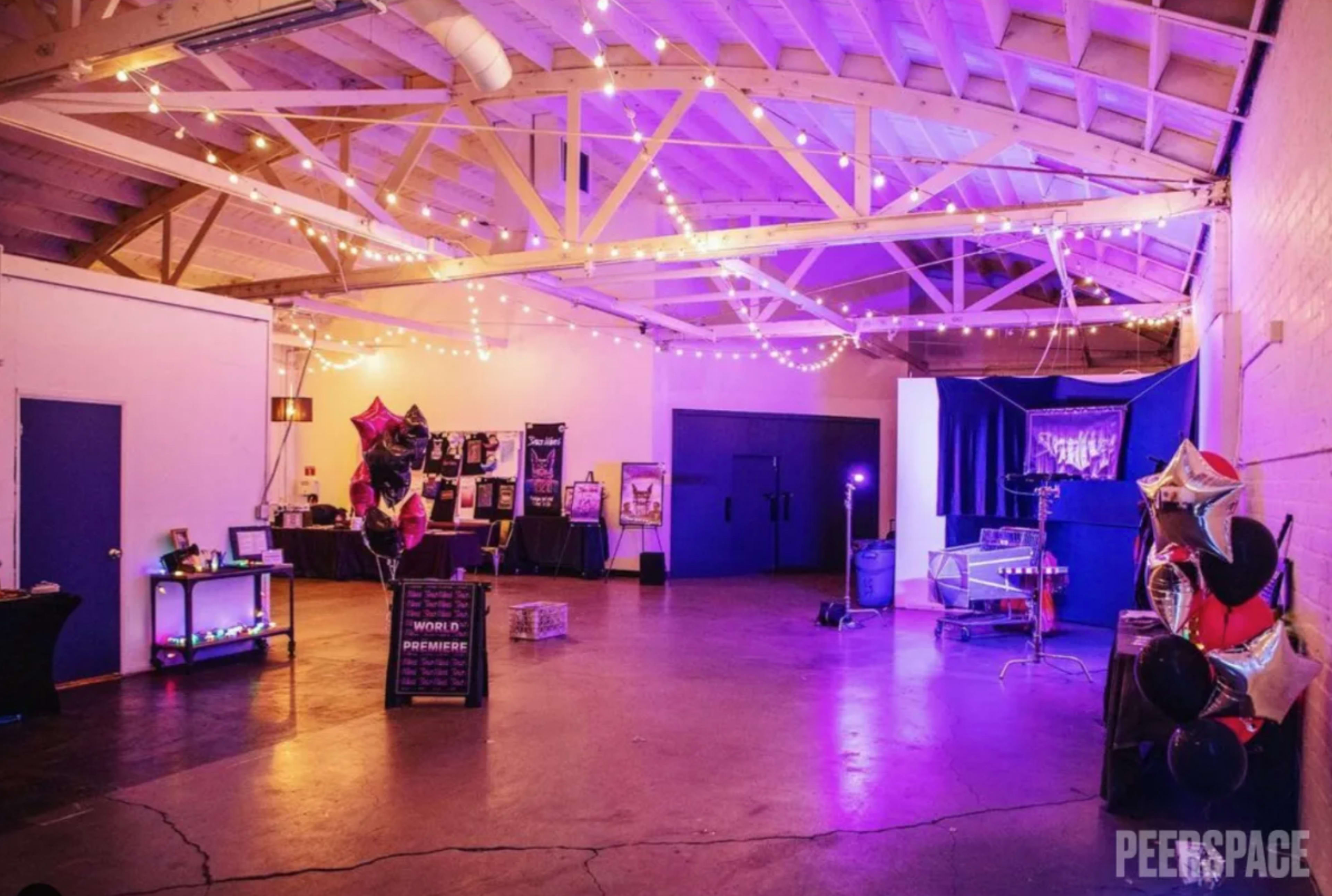 An event space decorated with string lights, colorful balloons, and various displays set up for a celebration.