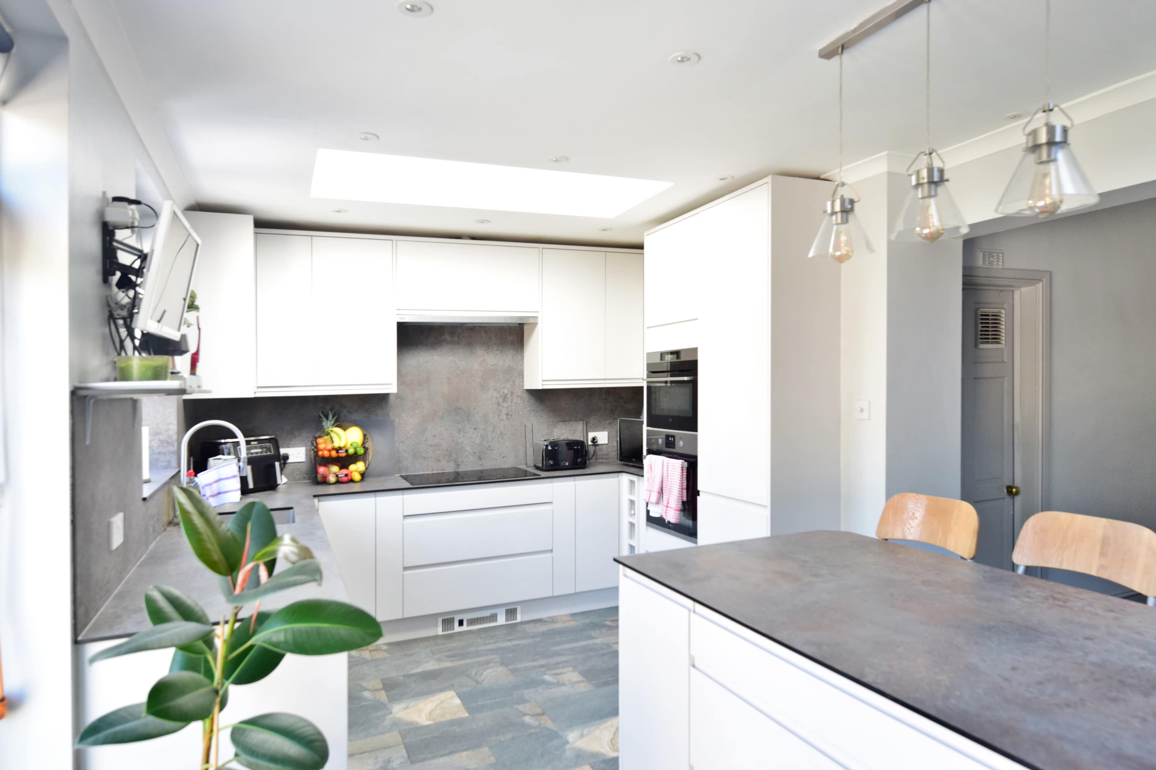 A modern kitchen features white cabinetry, a dark countertop, and pendant lighting above an island.