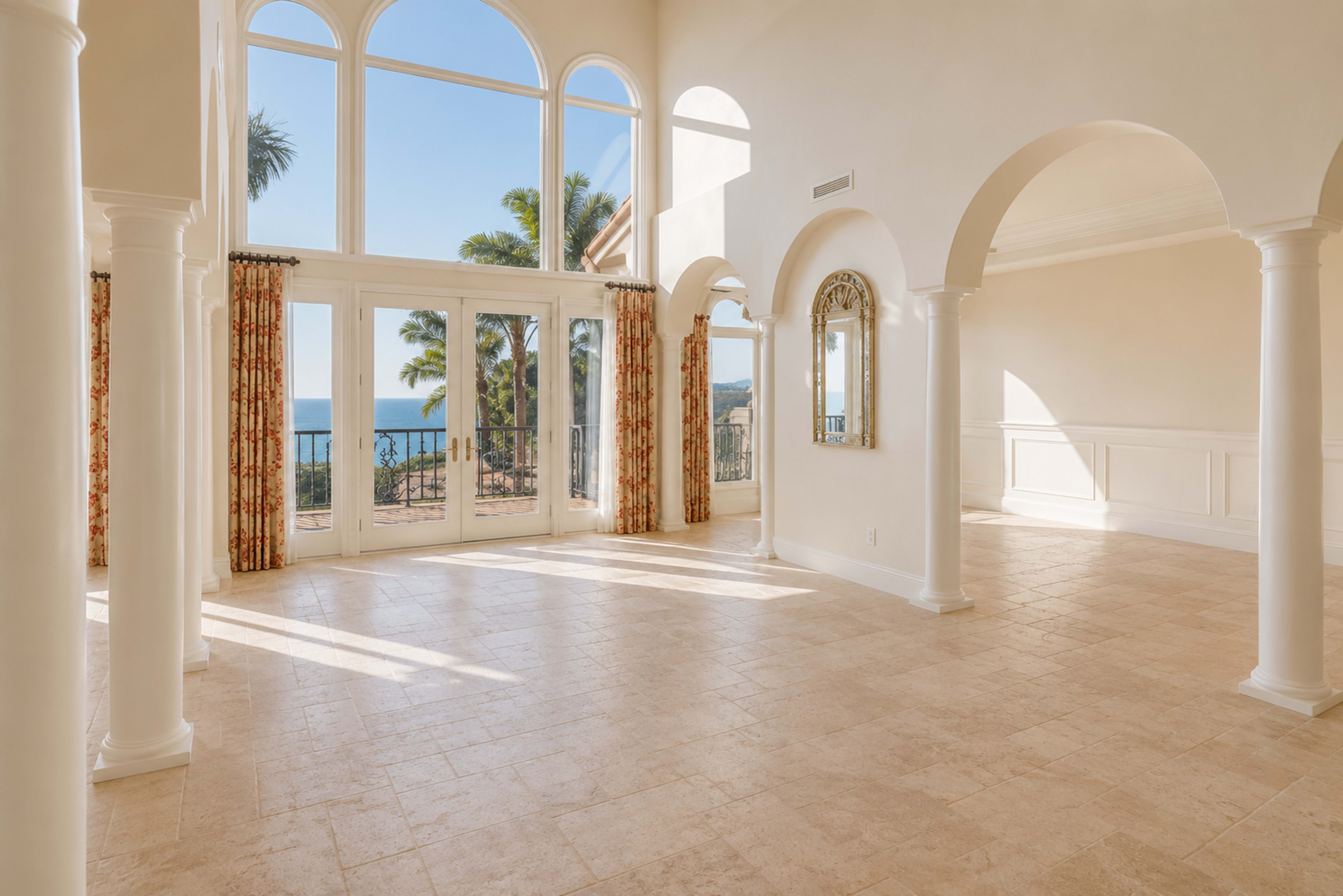 A spacious interior features tall windows that provide a view of the ocean and natural light filling the room.