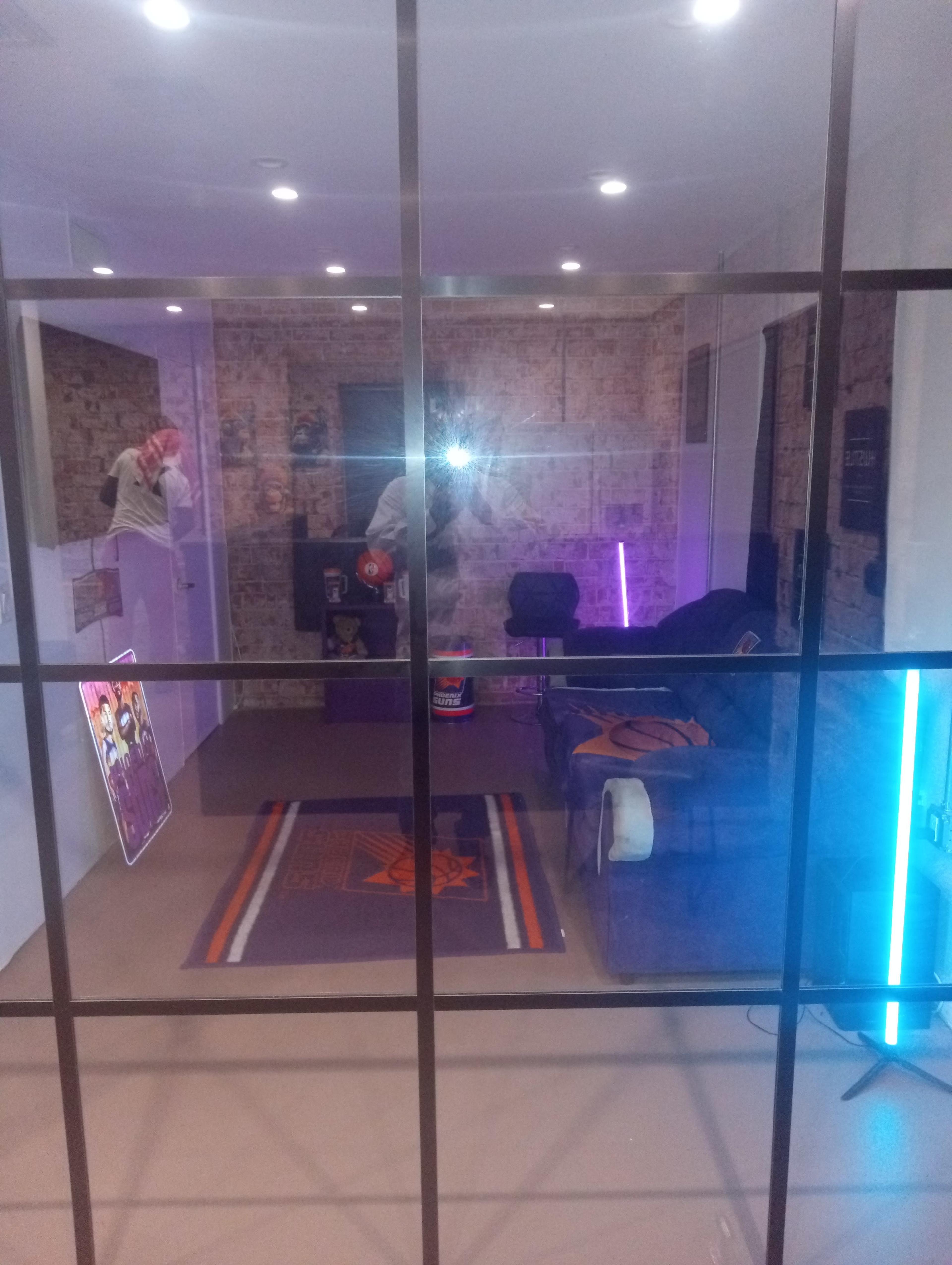 The image shows a modern, well-lit room with a brick accent wall, a couch, and colorful neon lights.